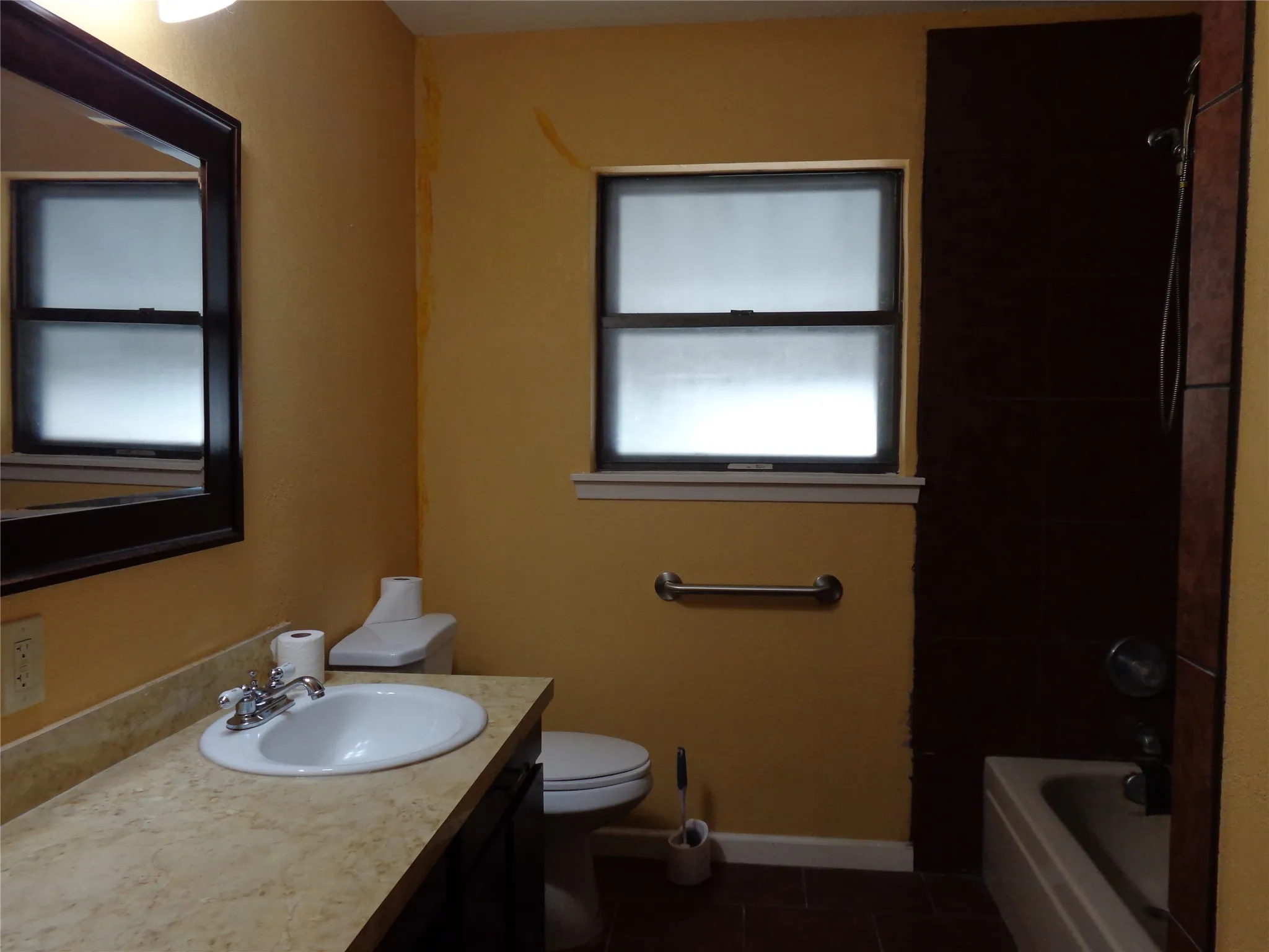 Vanity with built-in sink, framed mirror, and tiled bathtub surround