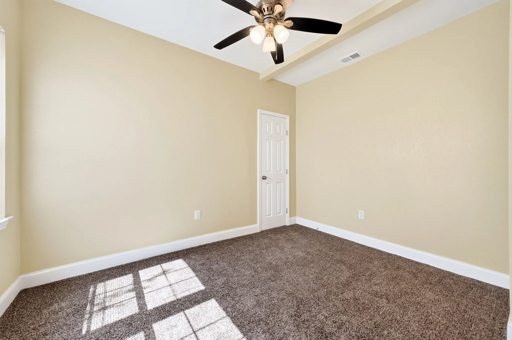 Tray ceiling with a ceiling fan, light beige walls, brown carpet flooring, and white trim