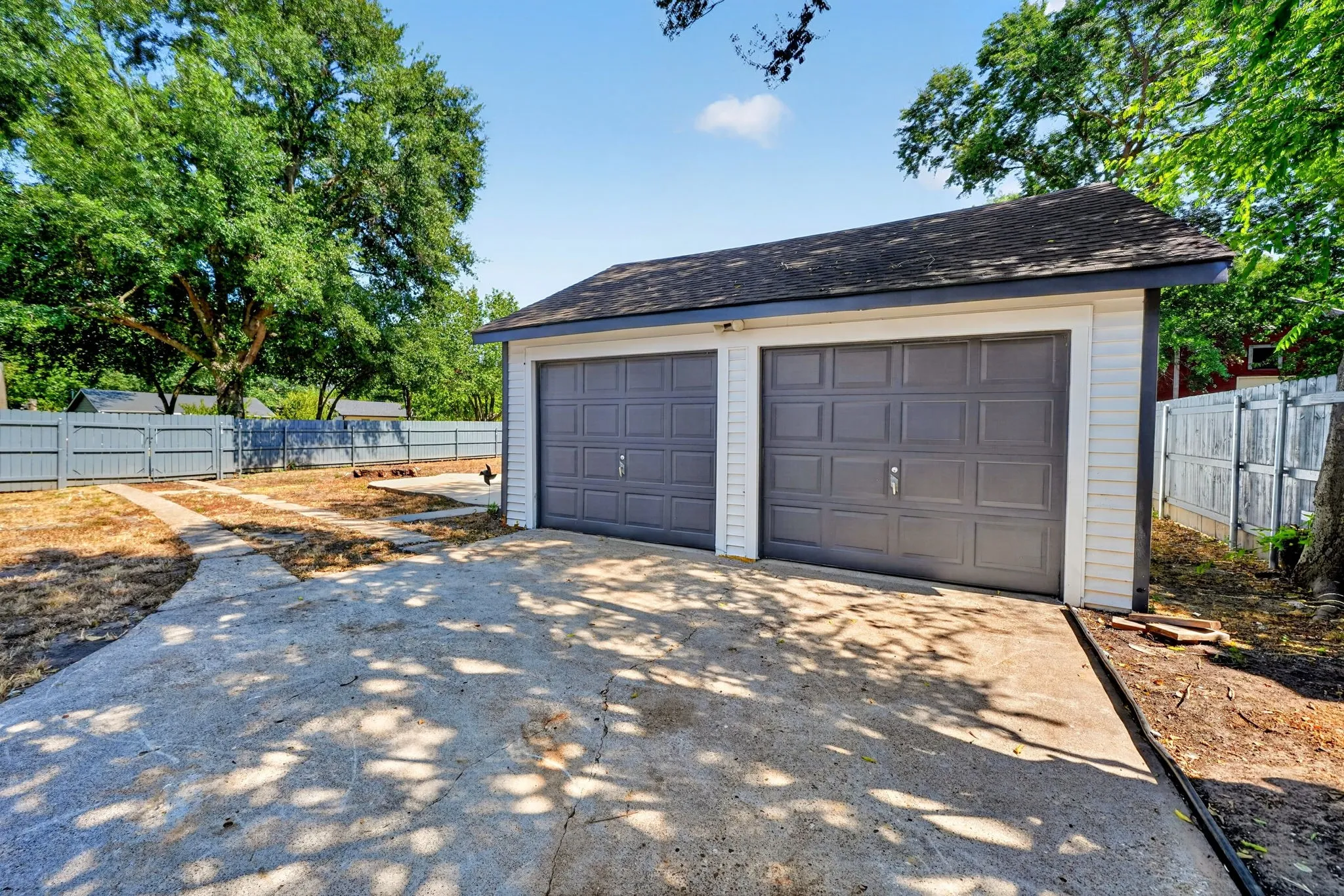 Detached two-car garage with panel-style doors and shingle roofing