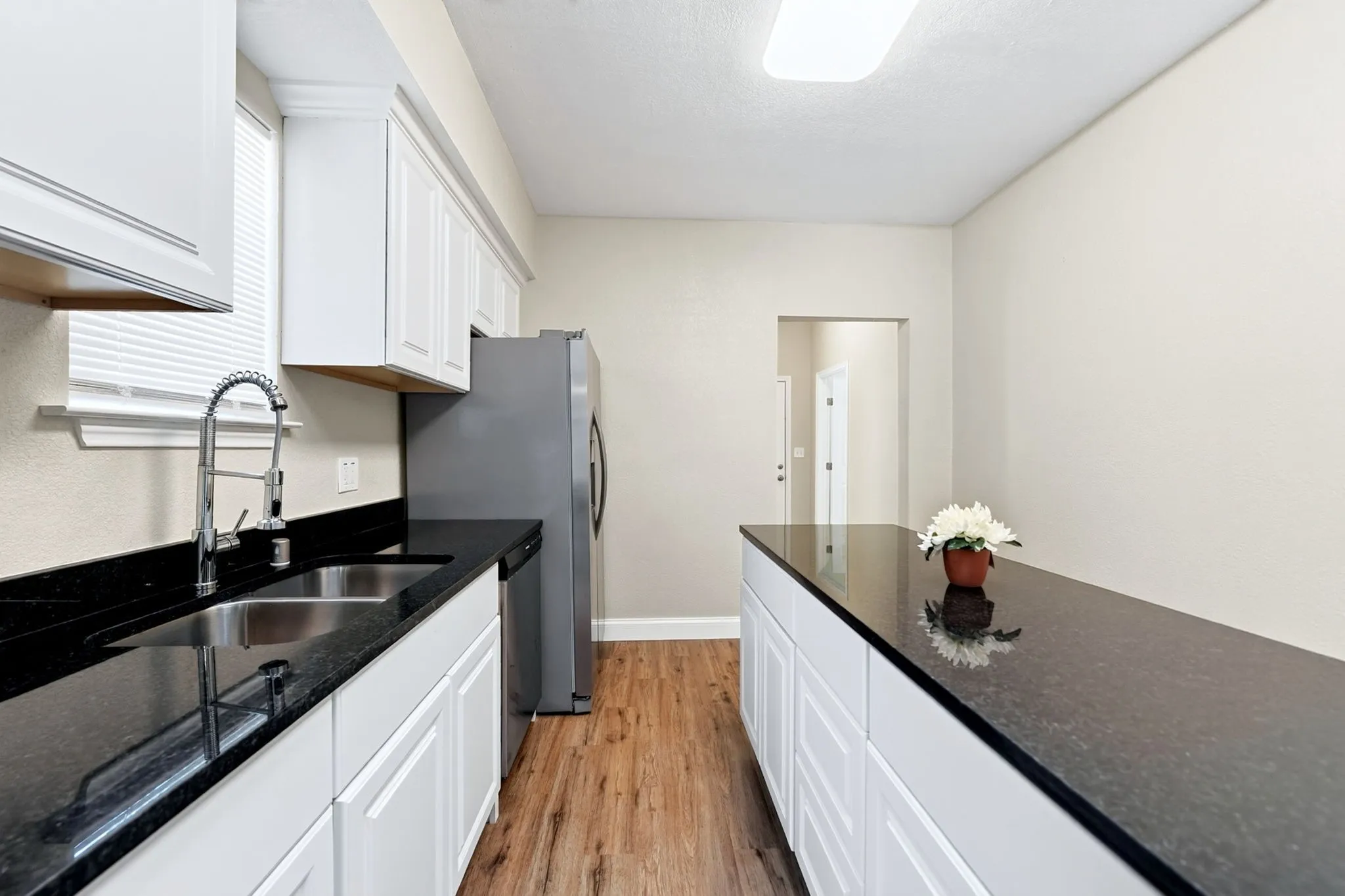 Kitchen featuring wood-finish flooring, white cabinetry, dark countertops, and stainless steel appliances