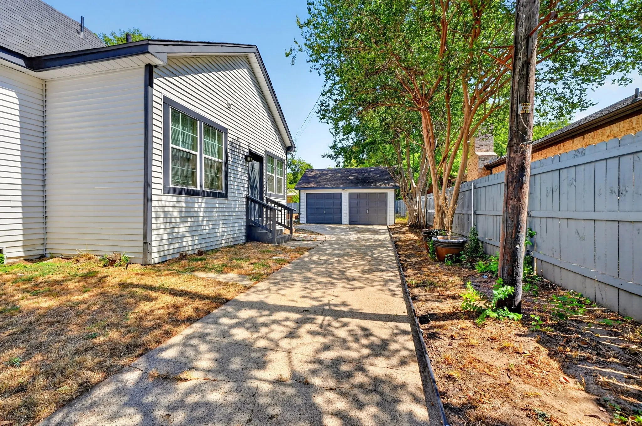 Concrete driveway leading to a detached two-car garage with panel doors