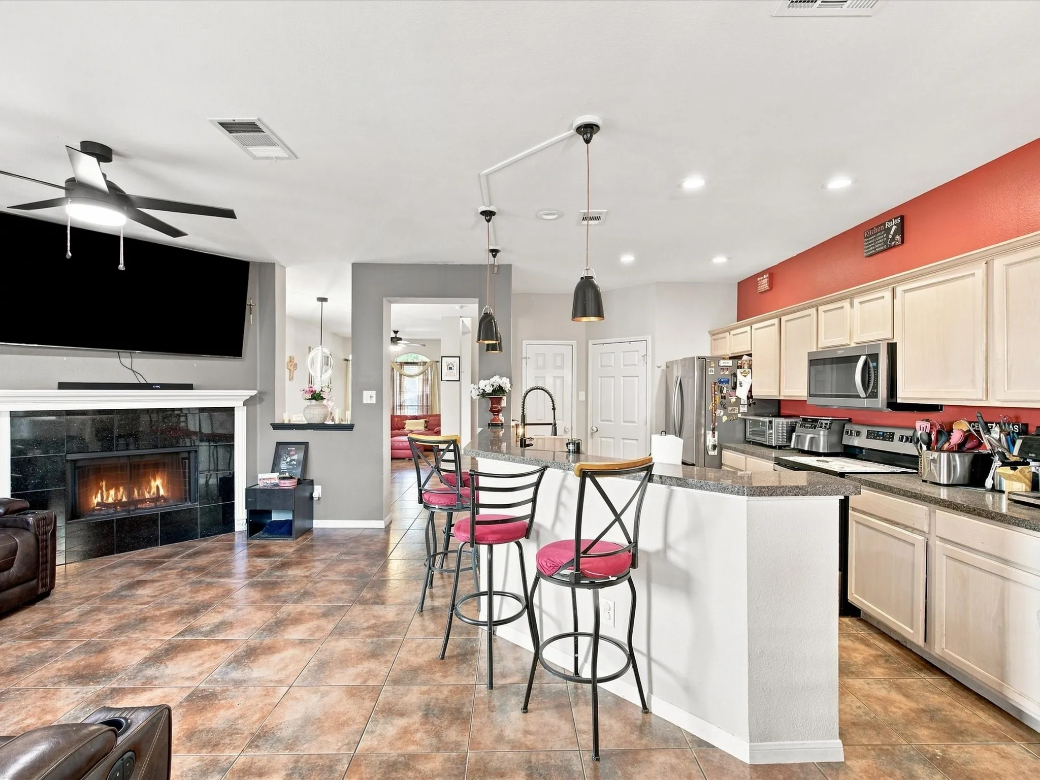 Integrated kitchen and living area featuring a central island, recessed lighting, and a fireplace with a black tile surround
