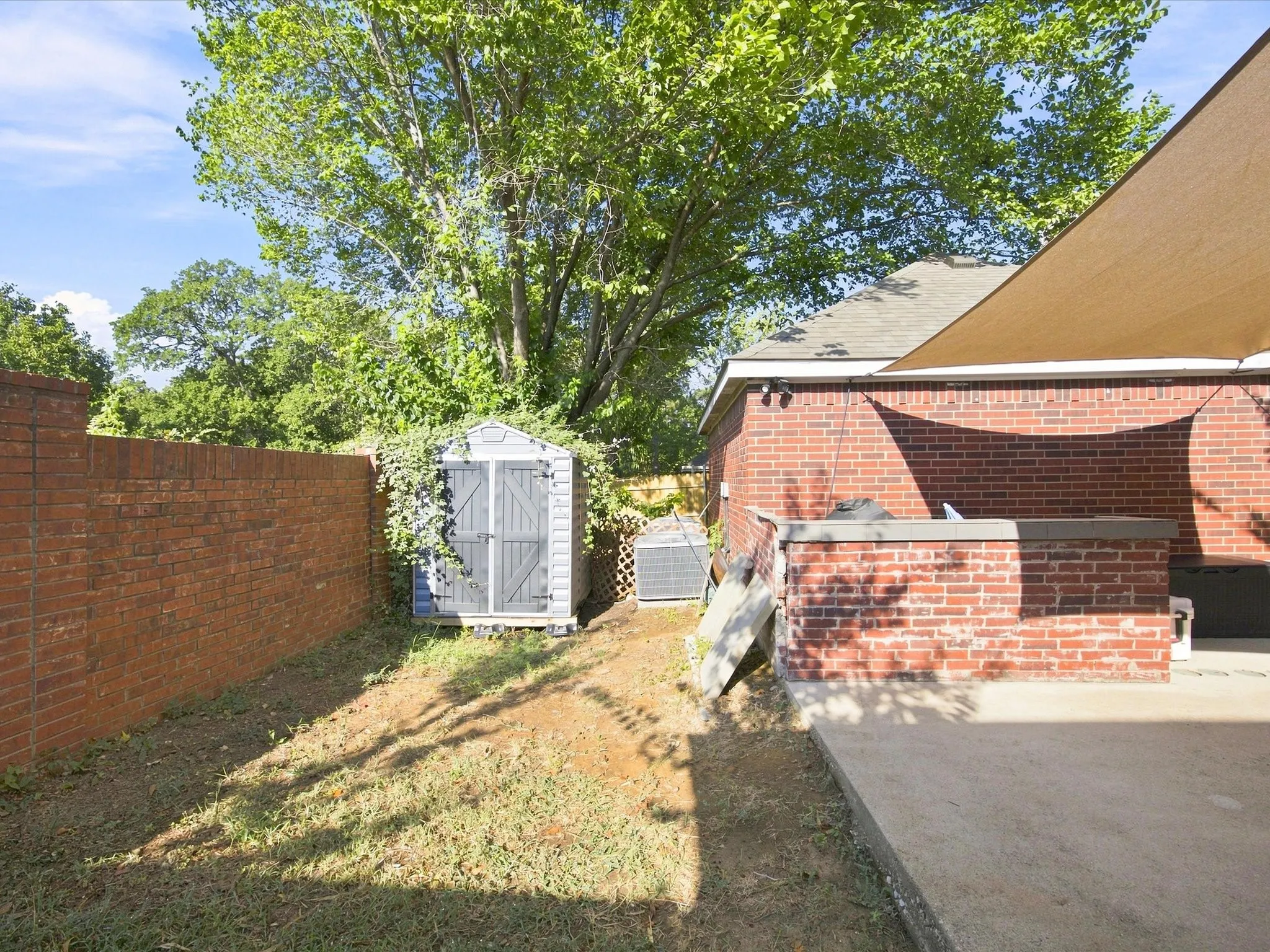 Brick exterior construction, concrete patio, a storage shed, and a privacy wall