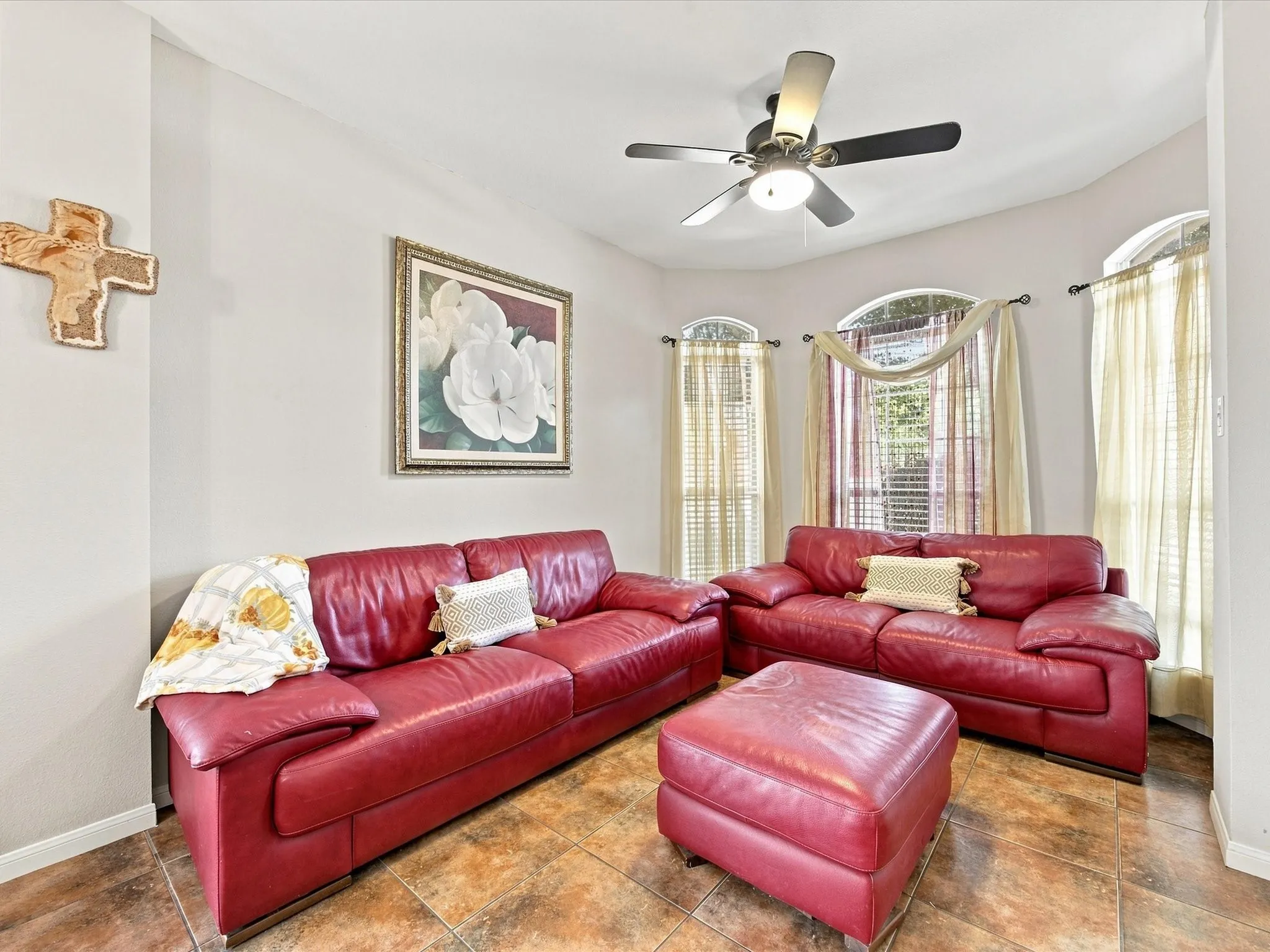 Arched windows, tile flooring, ceiling fan with integrated lighting, and neutral wall tones