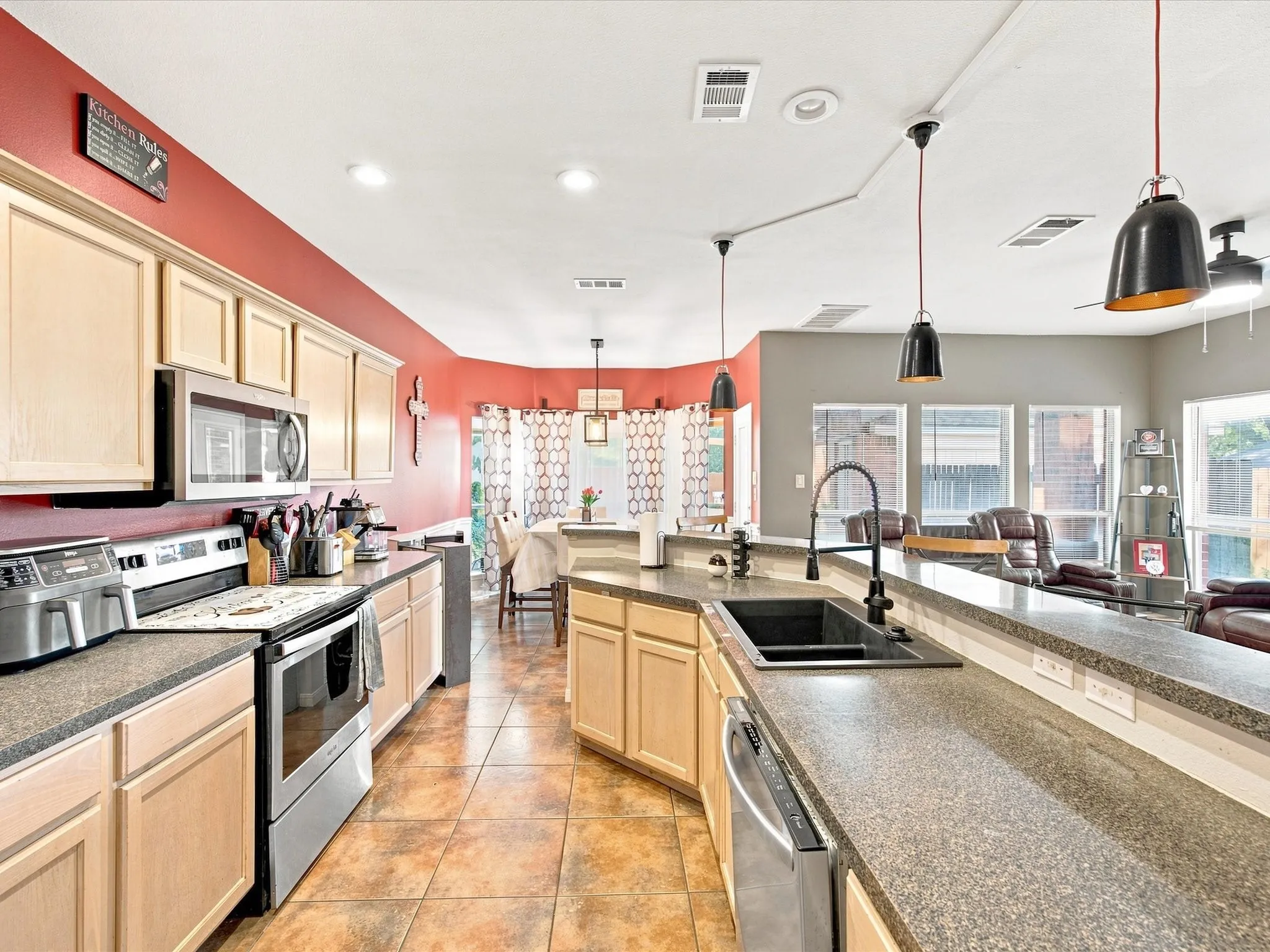 Kitchen featuring light wood-finish cabinetry, stainless steel appliances, speckled countertops, and tile flooring