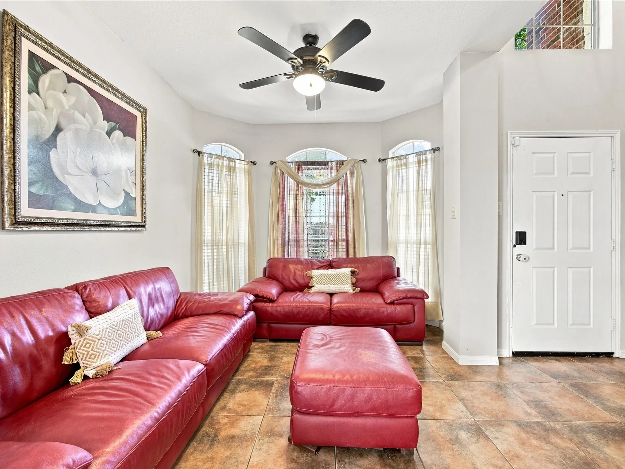 Bay window with arched transoms, tile flooring, and ceiling fan