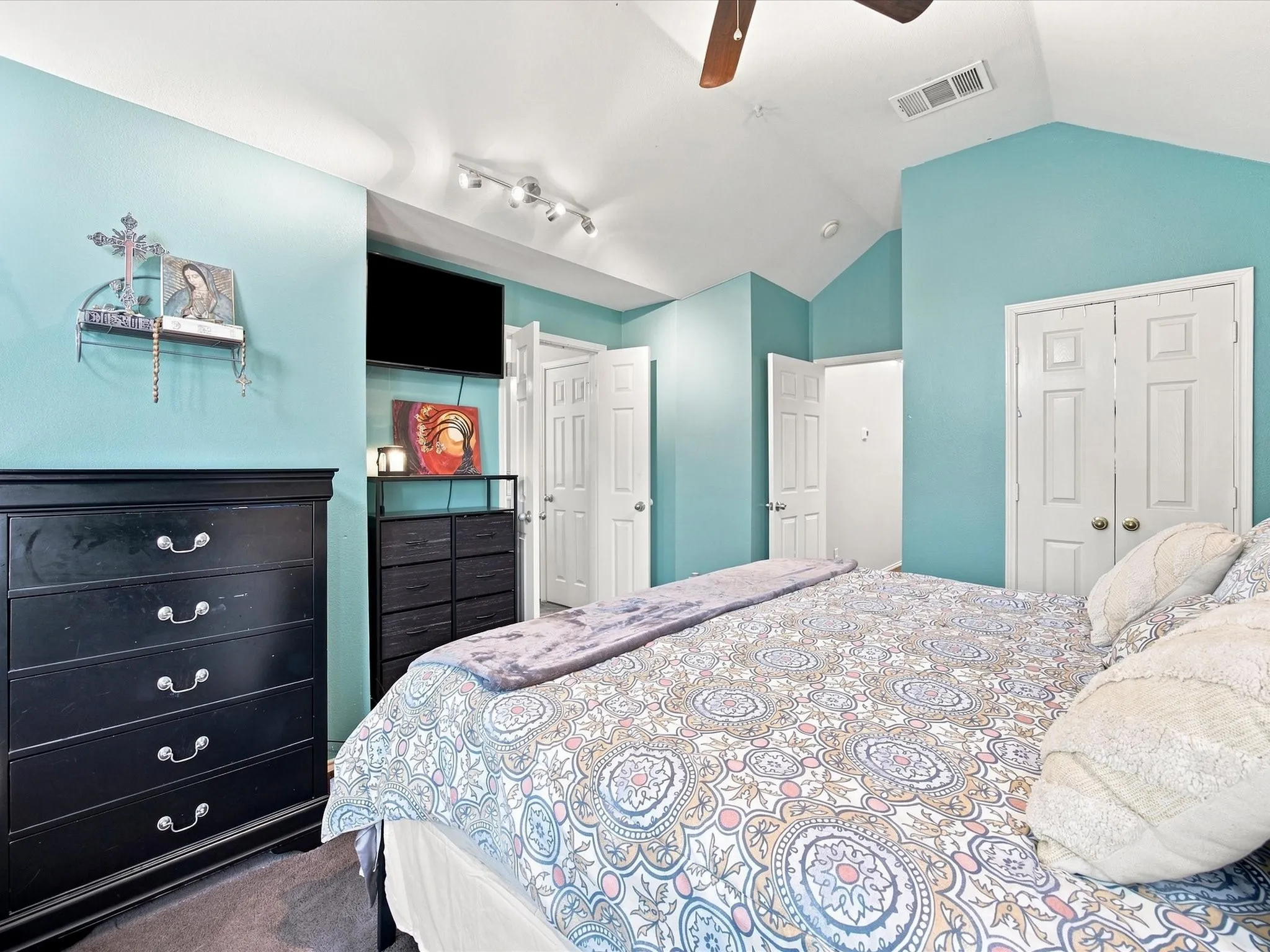 Vaulted ceiling with a ceiling fan, track lighting, and two panel doors