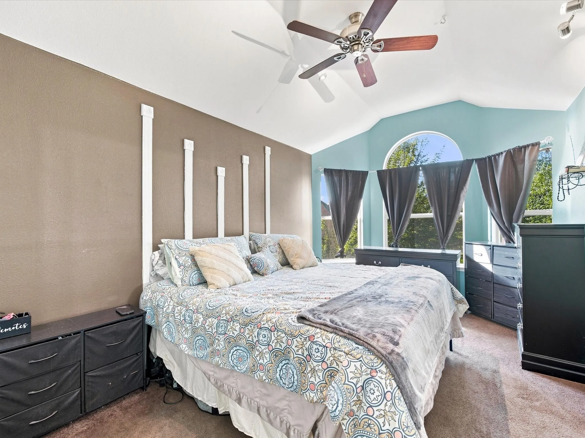 Vaulted ceiling with a ceiling fan, arched window, and carpeted flooring