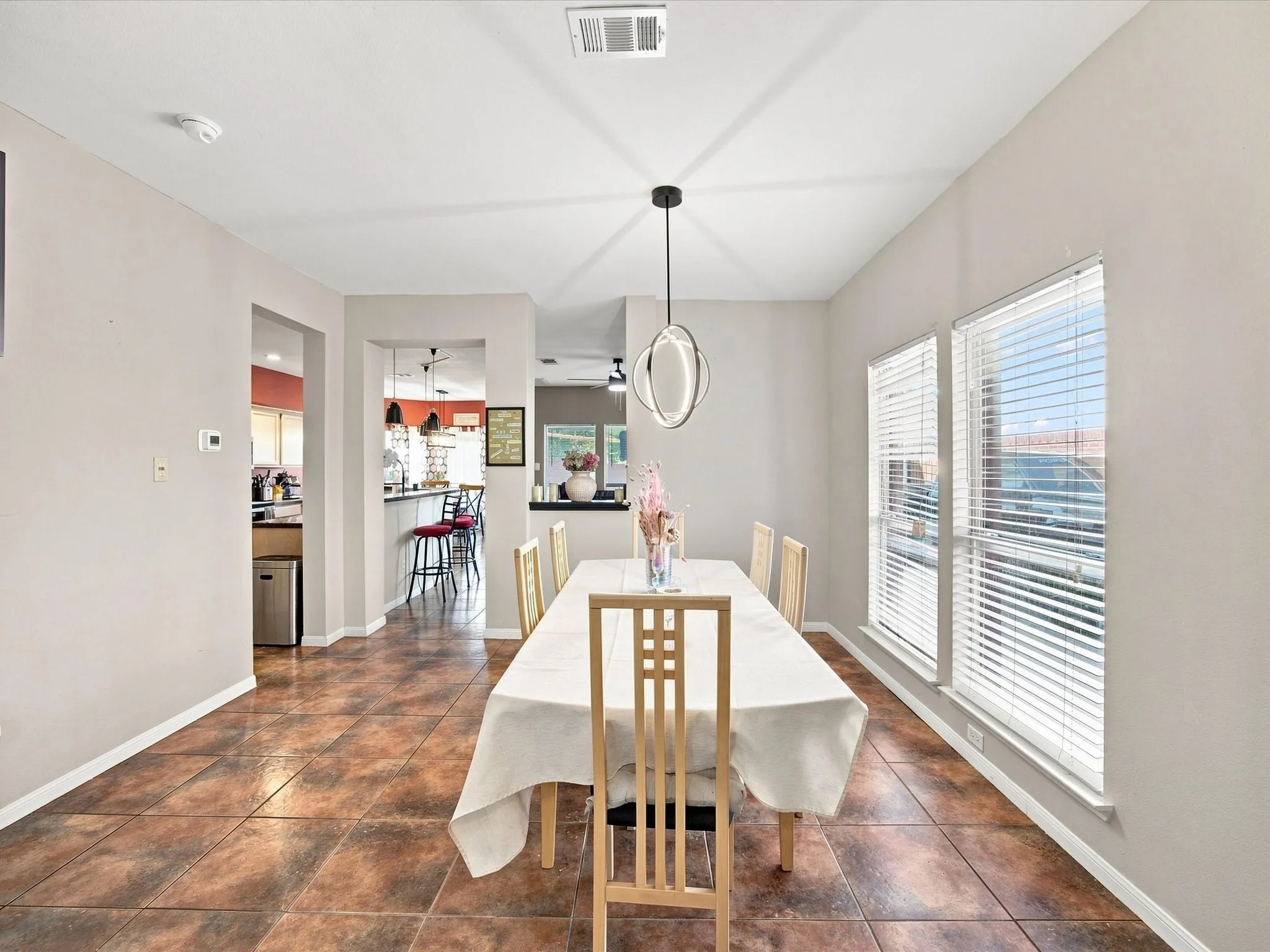 Tile flooring, recessed lighting, contemporary pendant light fixture, and multiple windows with blinds