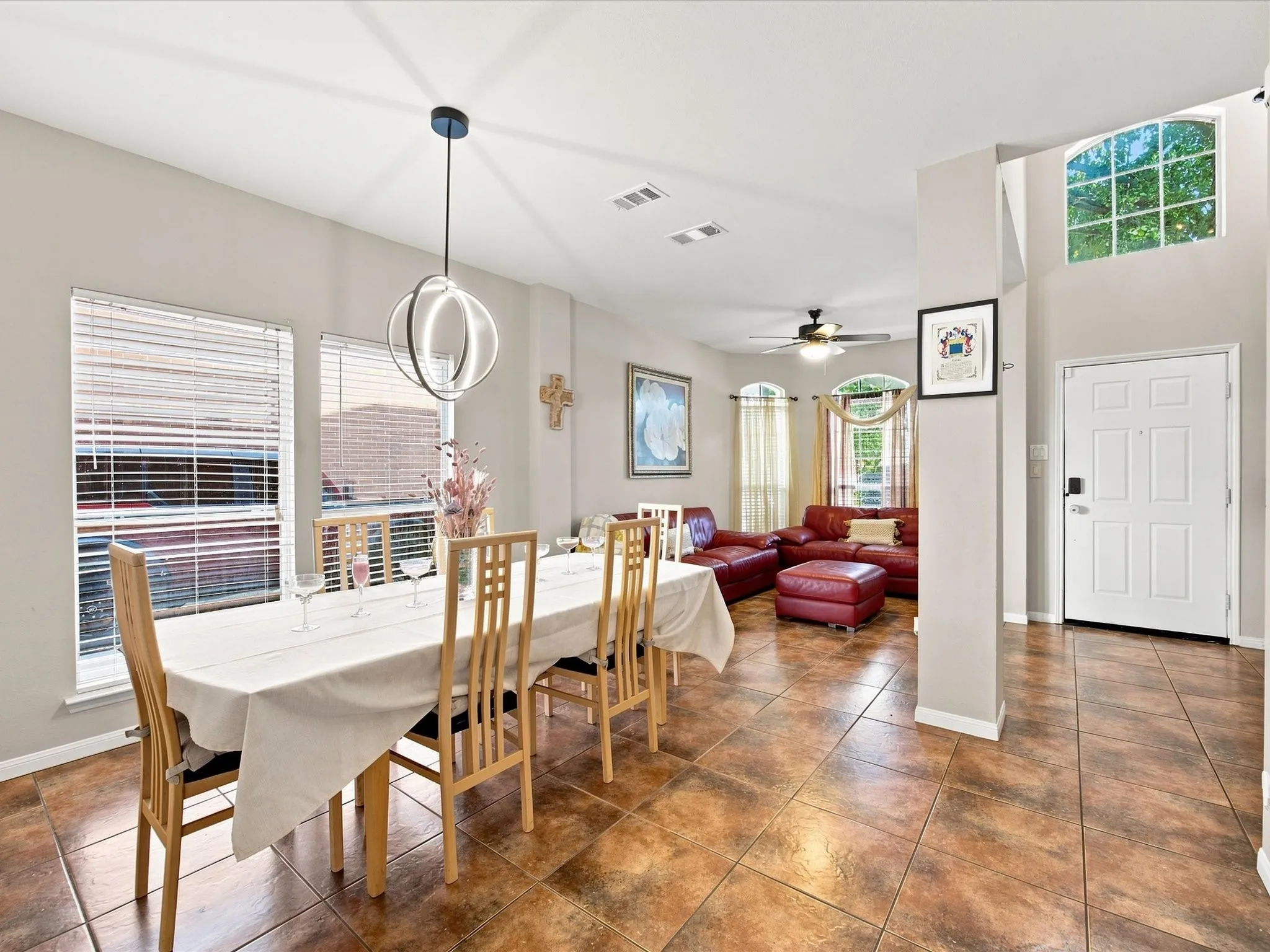 Open-concept living area featuring tile flooring, a modern spherical chandelier, a ceiling fan, and multiple windows