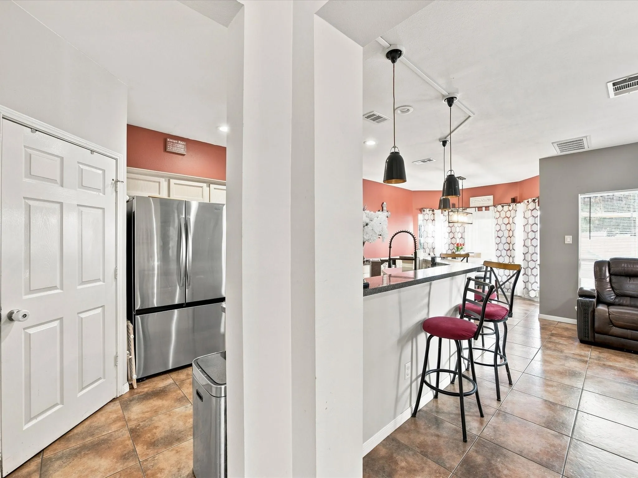 Kitchen featuring stainless steel refrigerator, white cabinetry, and a peninsula with dark countertops