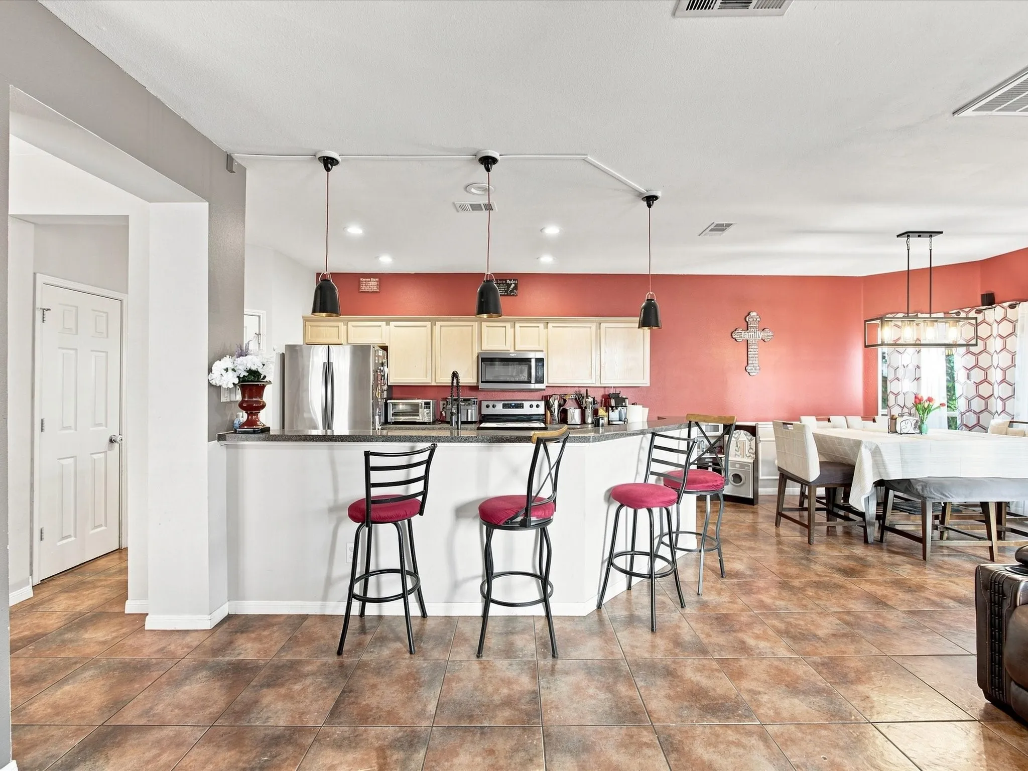 Tiled flooring throughout, kitchen peninsula with counter seating, stainless steel appliances, upper and lower cabinetry, and recessed lighting