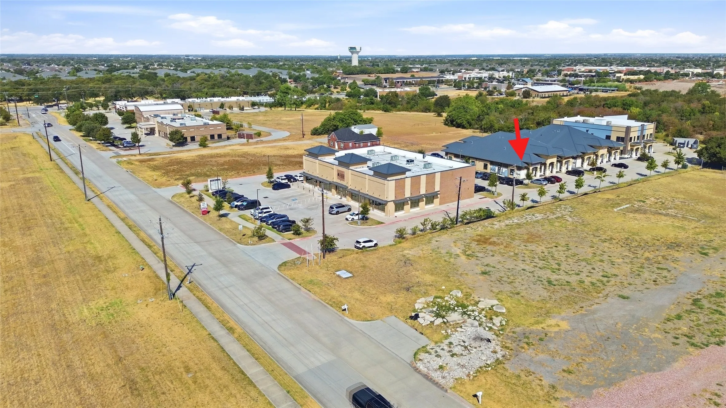 Commercial building with multiple units, ample parking, and surrounding undeveloped land