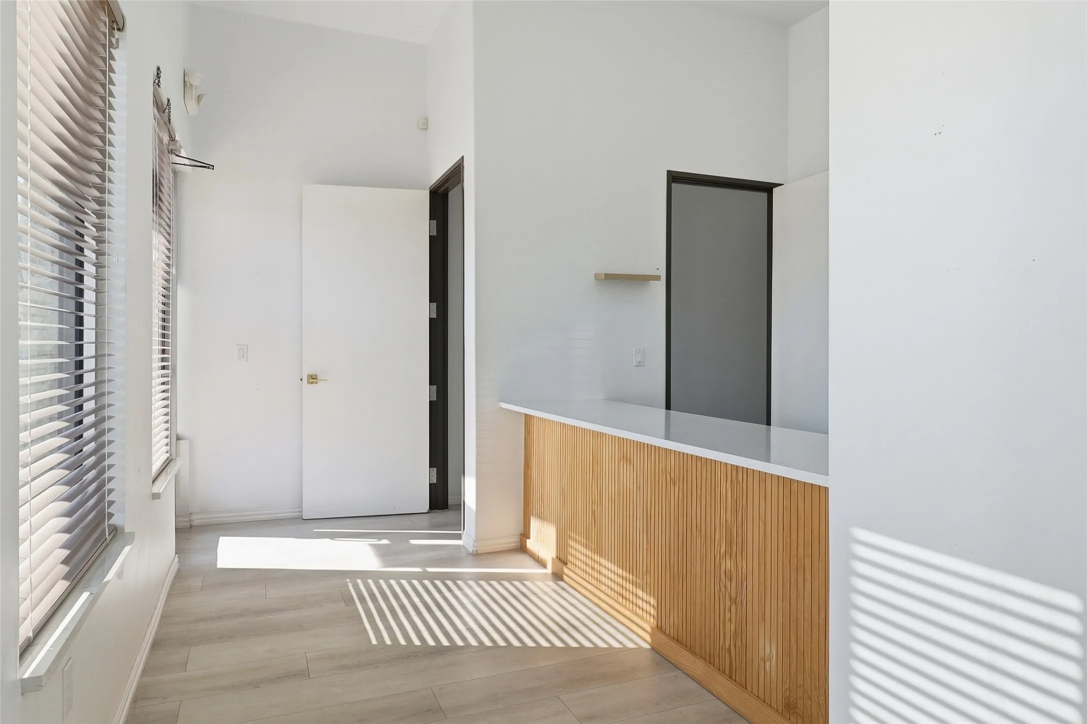 Light wood-finish flooring with white walls and a vaulted ceiling