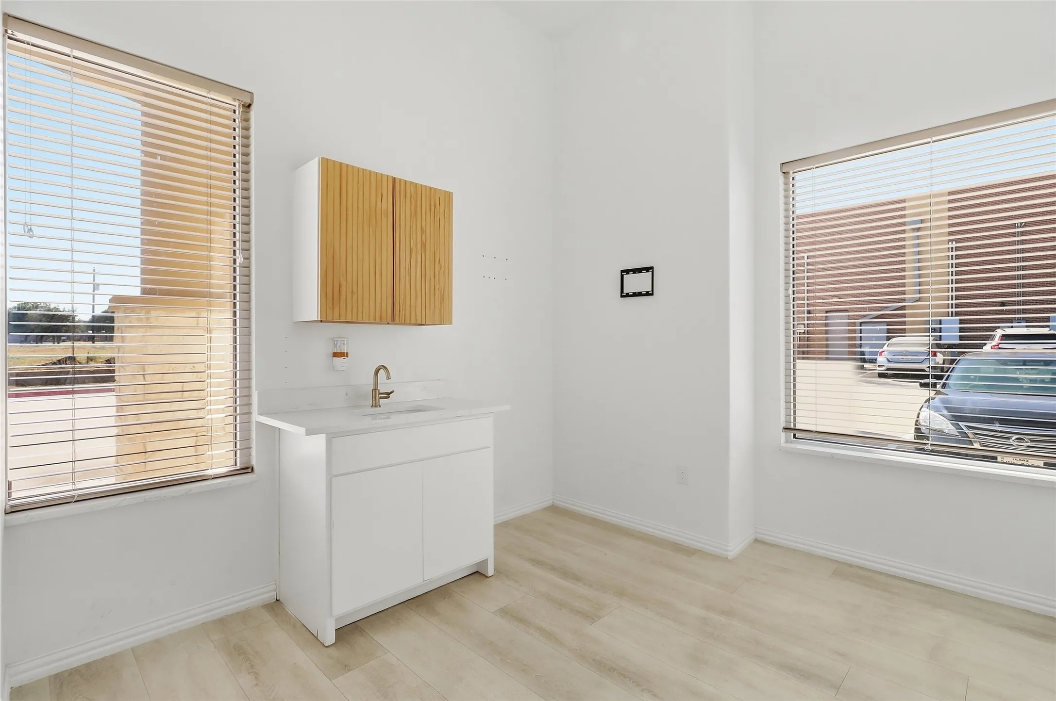 White vanity with a rectangular sink, gold-finish faucet, and white countertop