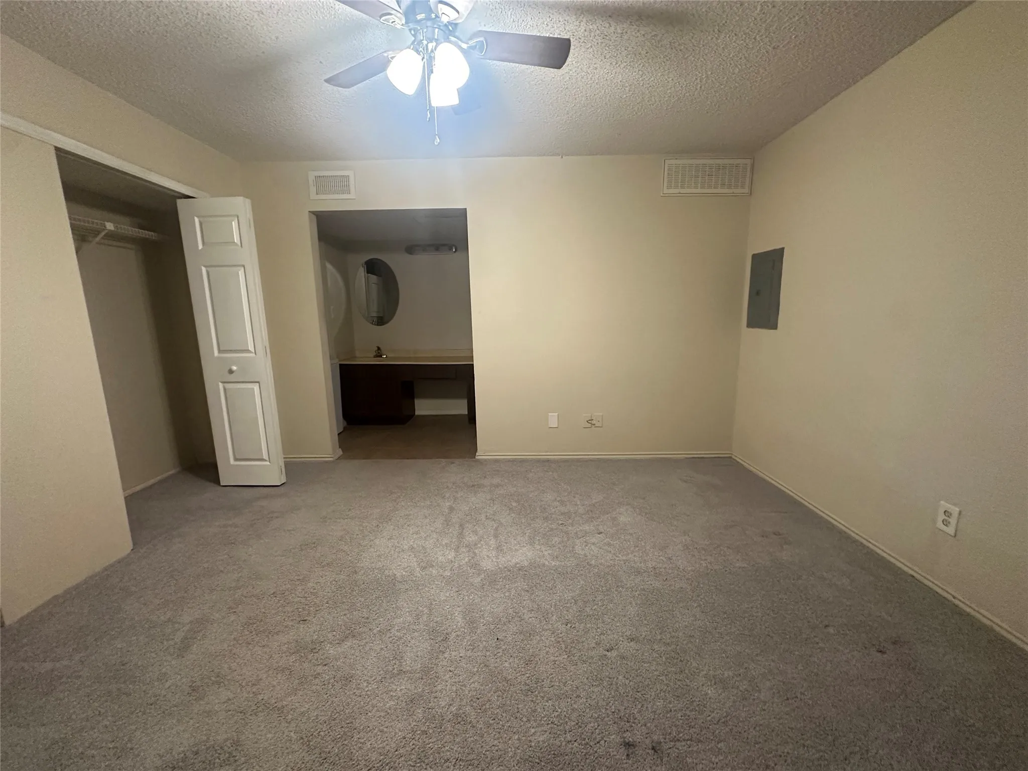 Recessed closet with hanging rod, ceiling fan with integrated lighting, built-in vanity with oval mirror, and carpeted flooring