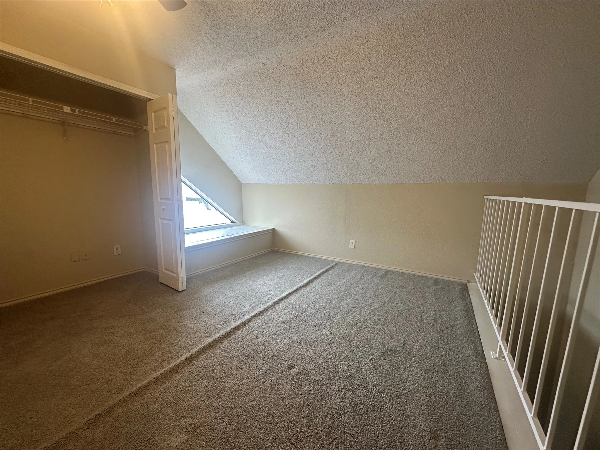Angled ceiling, built-in window seat, bi-fold closet doors, wall-to-wall carpeting, and white railing