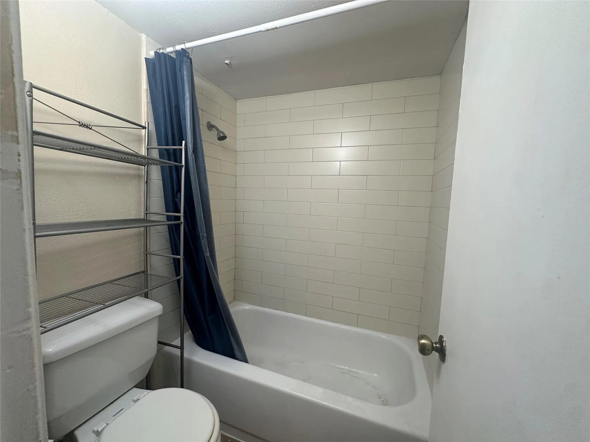 White subway tile shower surround with a built-in tub and shower fixture