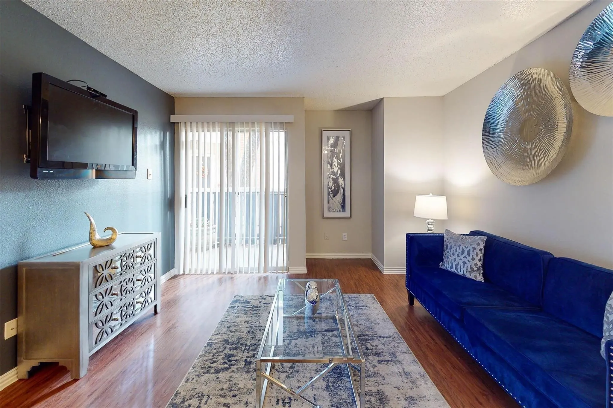 Wood-finish flooring throughout, sliding glass door with vertical blinds, and a built-in wall niche