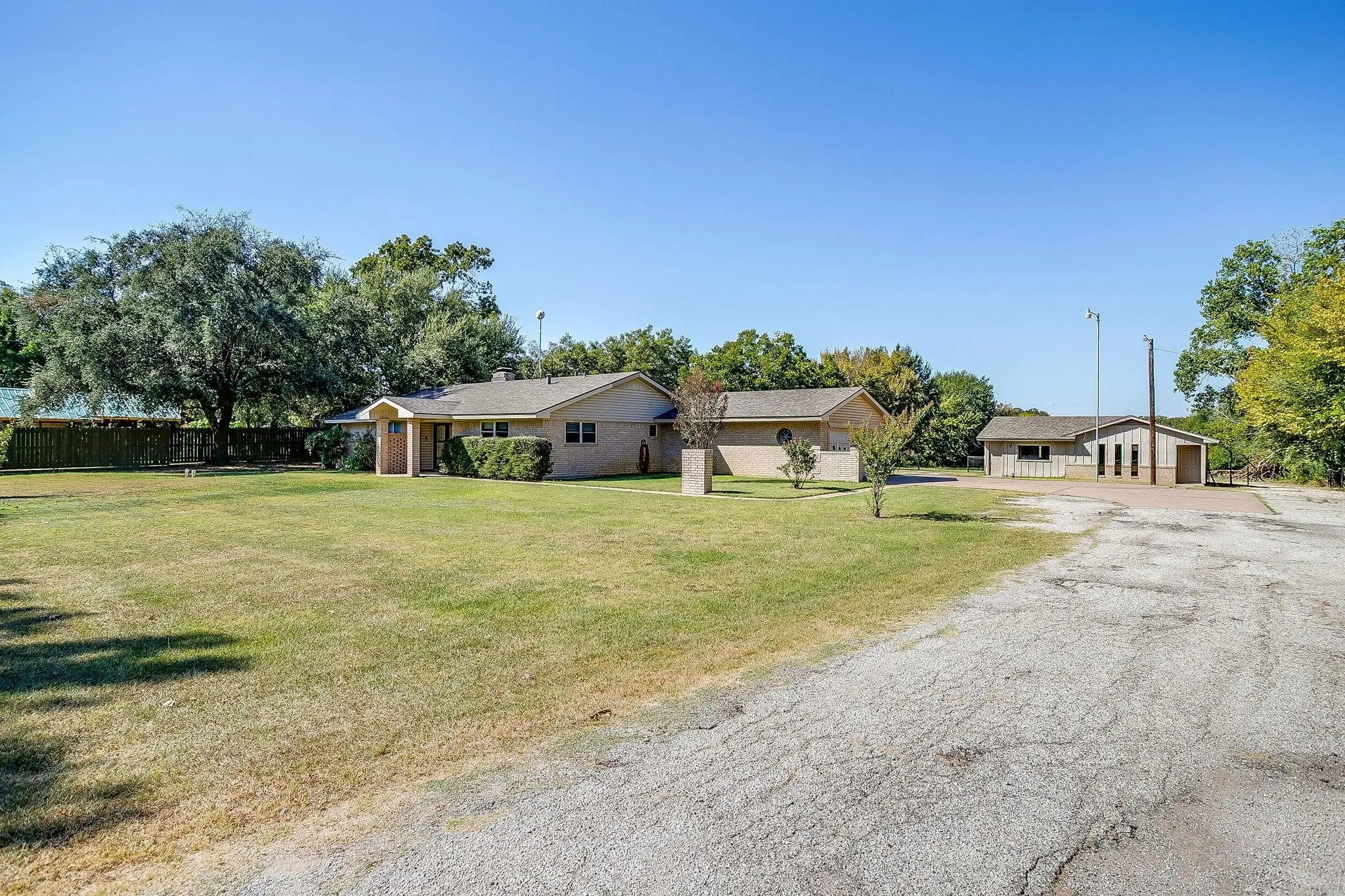 Brick exterior with a covered entry, mature landscaping, and a separate outbuilding