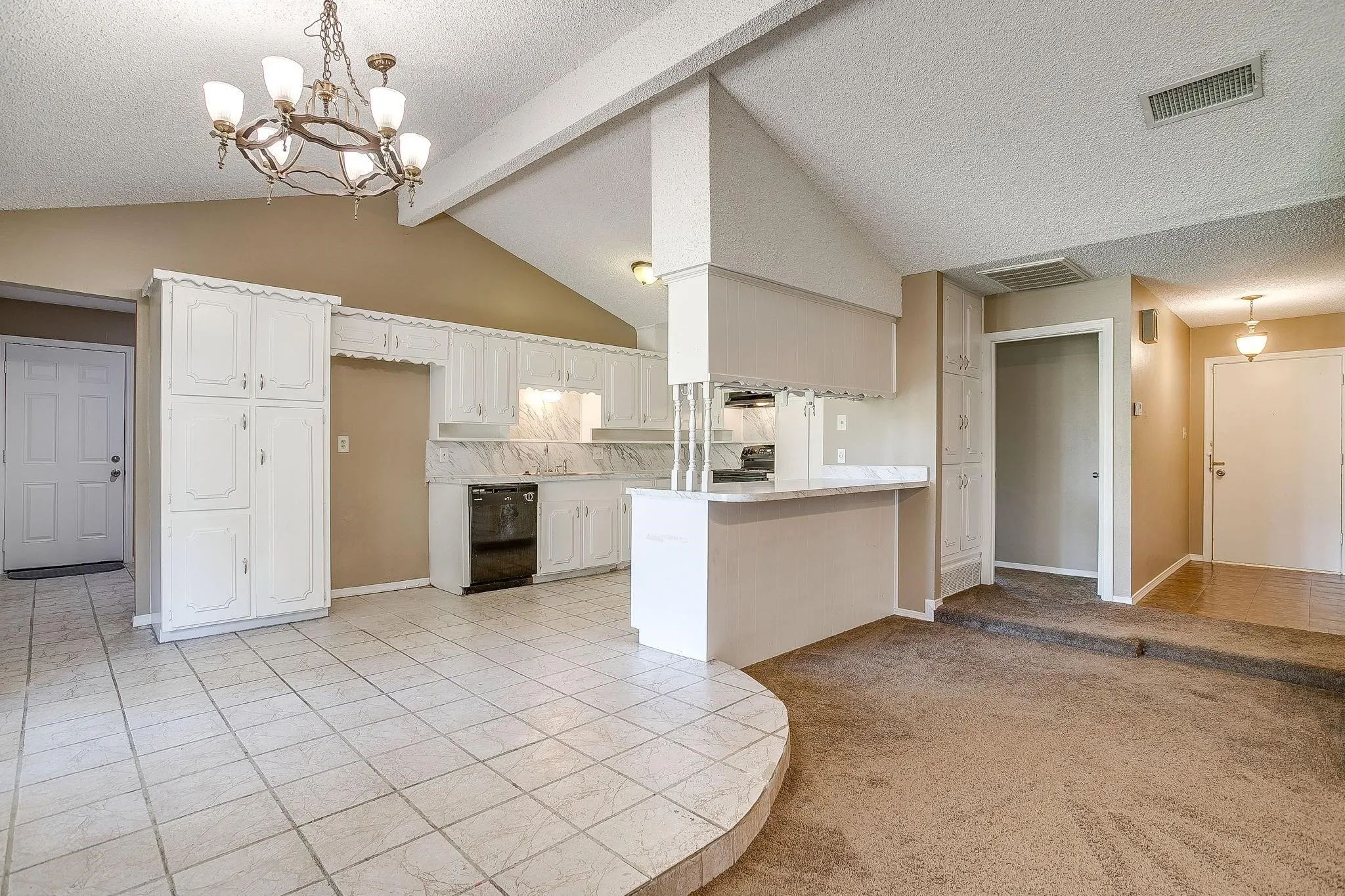 Vaulted ceilings with exposed beams, white cabinetry, a built-in kitchen peninsula with a white countertop, and tile flooring