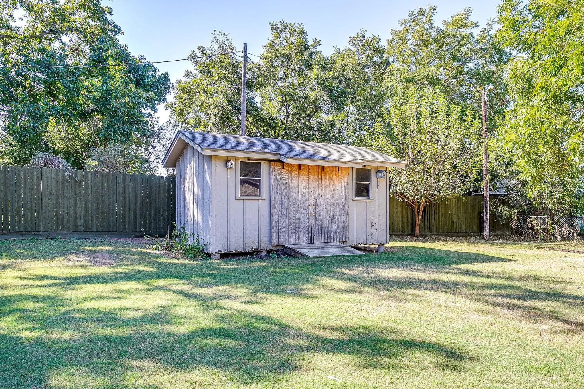 Storage shed with wood siding, single-hung windows, and a sloped roof