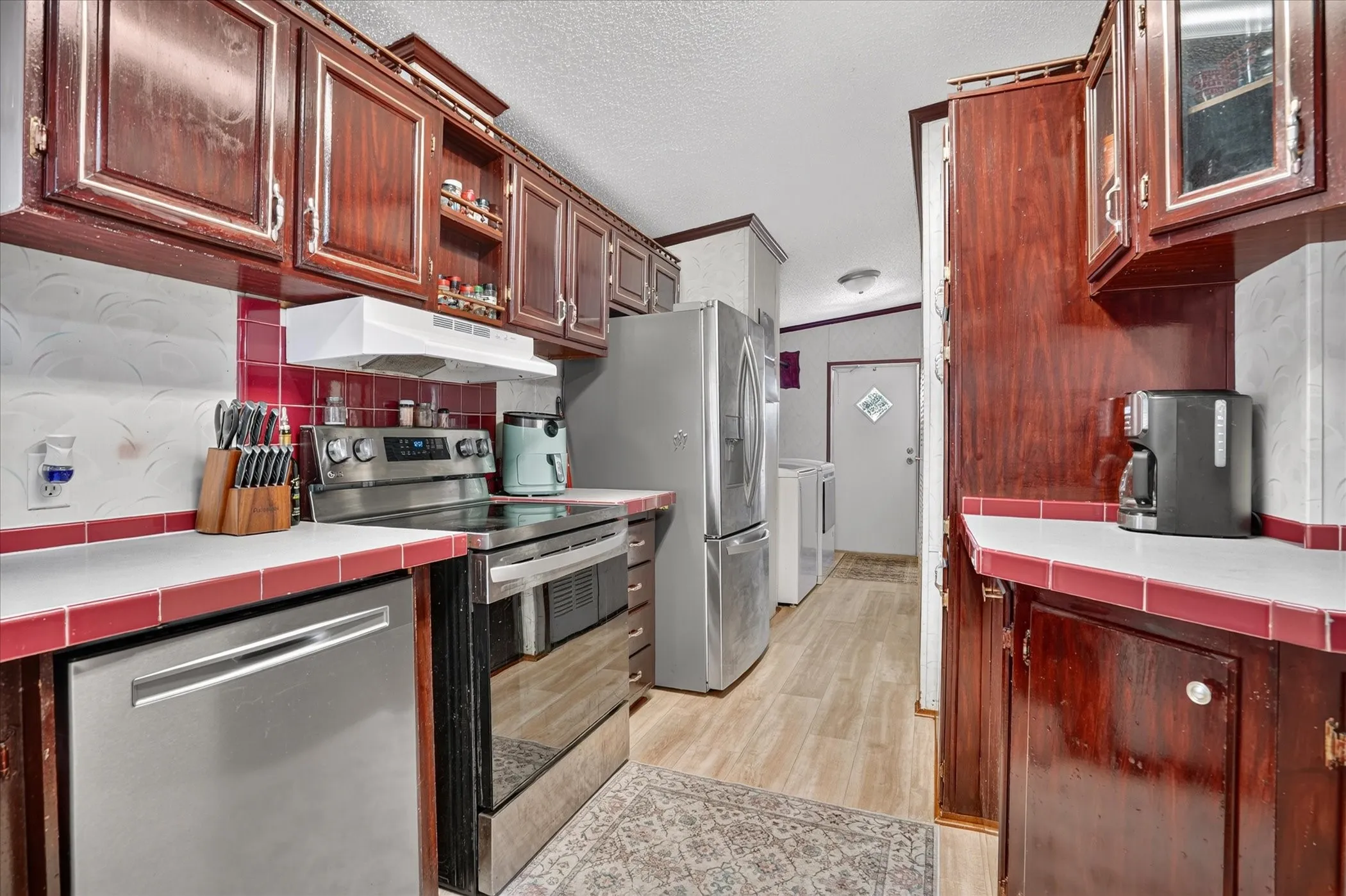 Kitchen featuring wood-finish cabinetry, stainless steel appliances, and tile countertops