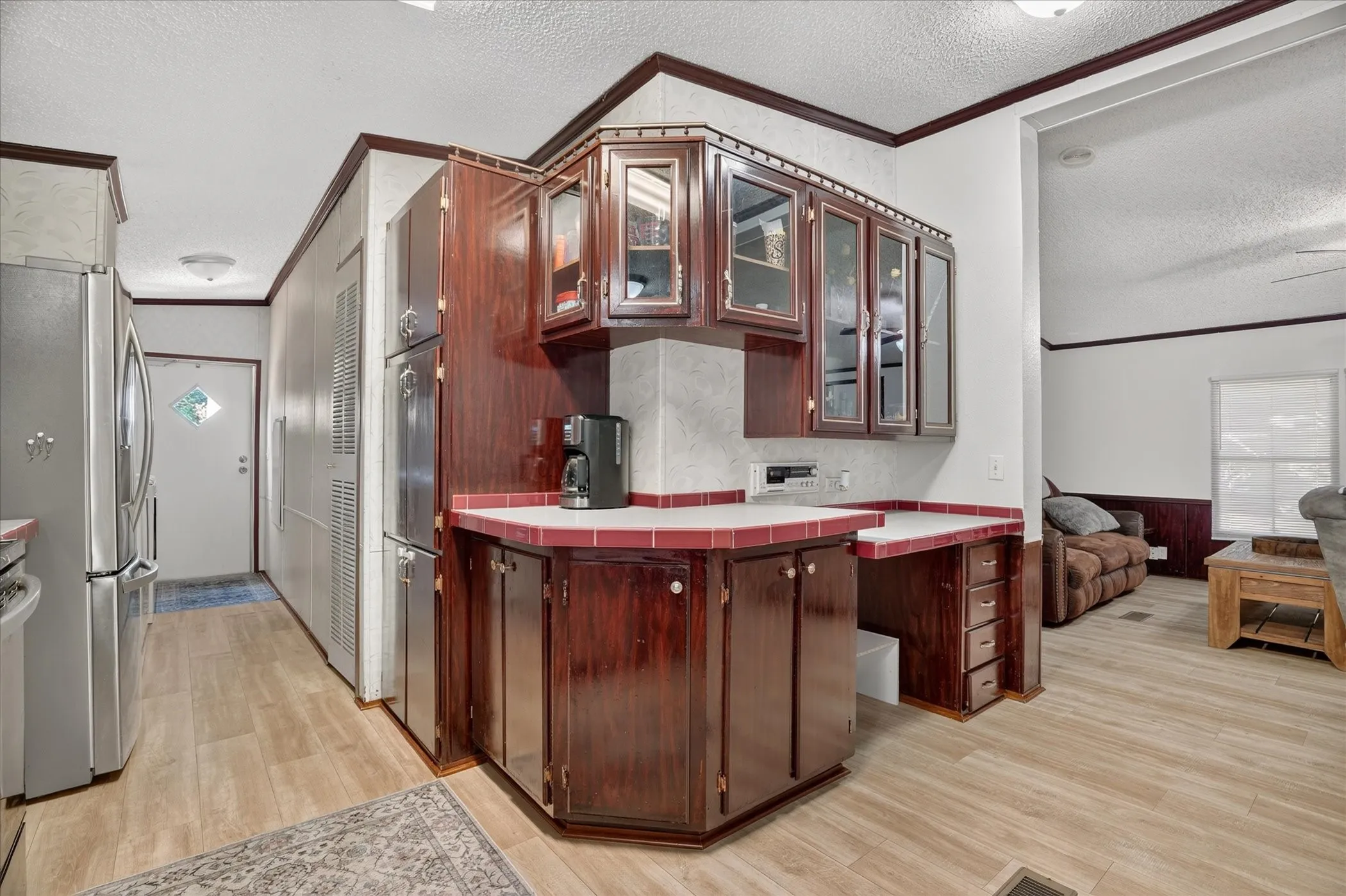 Integrated cabinetry with glass-front upper cabinets, tile countertops, and wood-finish flooring