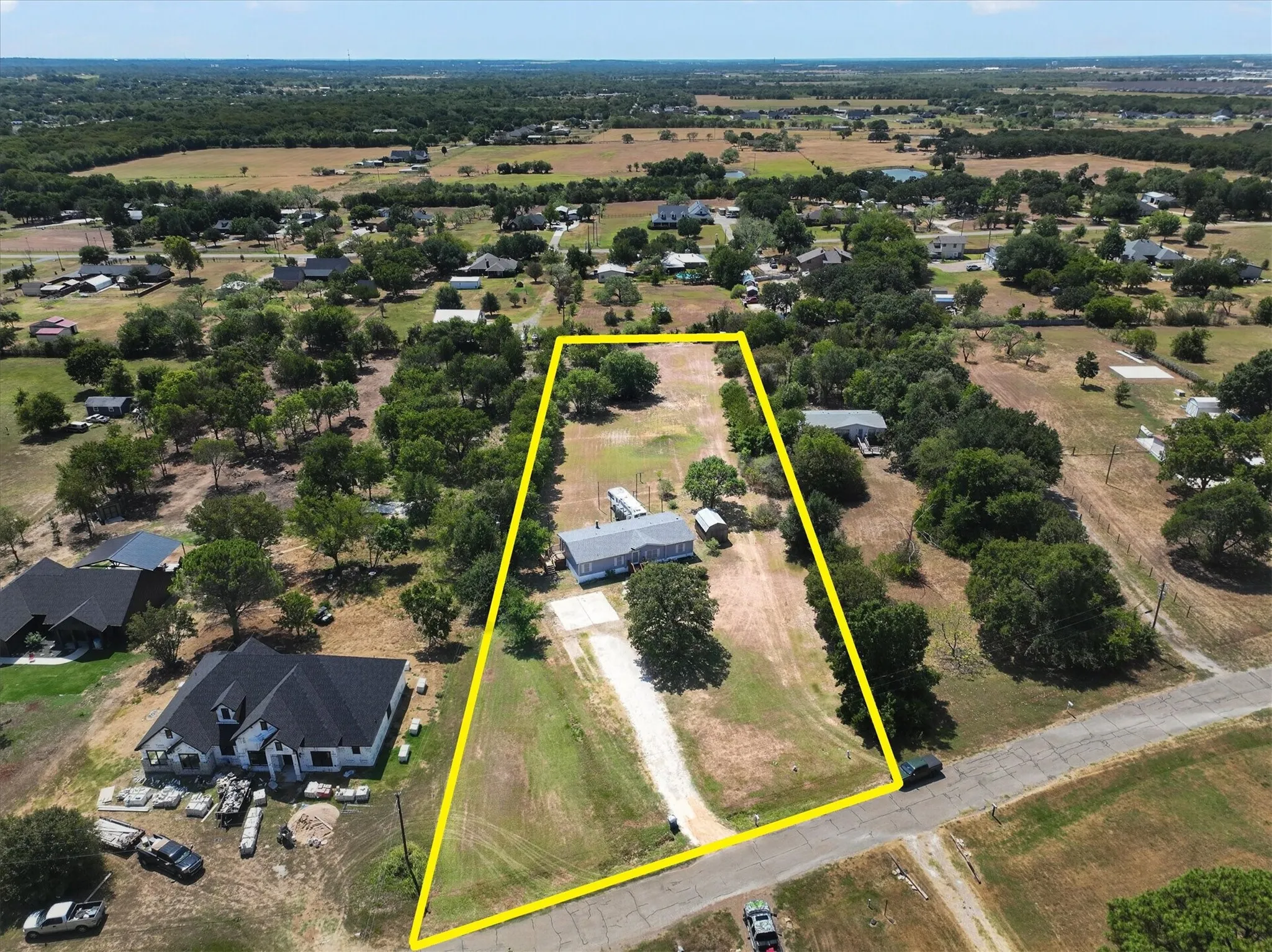 Expansive rural property featuring a main residence, mature trees, and a gravel driveway