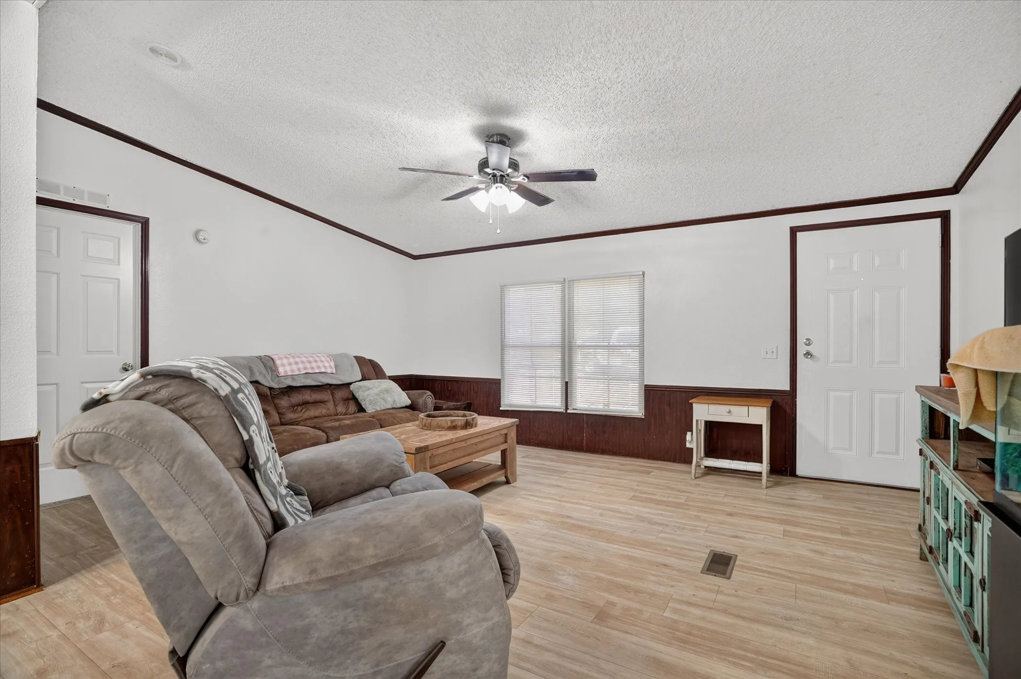 Wood-finish flooring, white walls with dark trim, ceiling fan, and white paneled doors