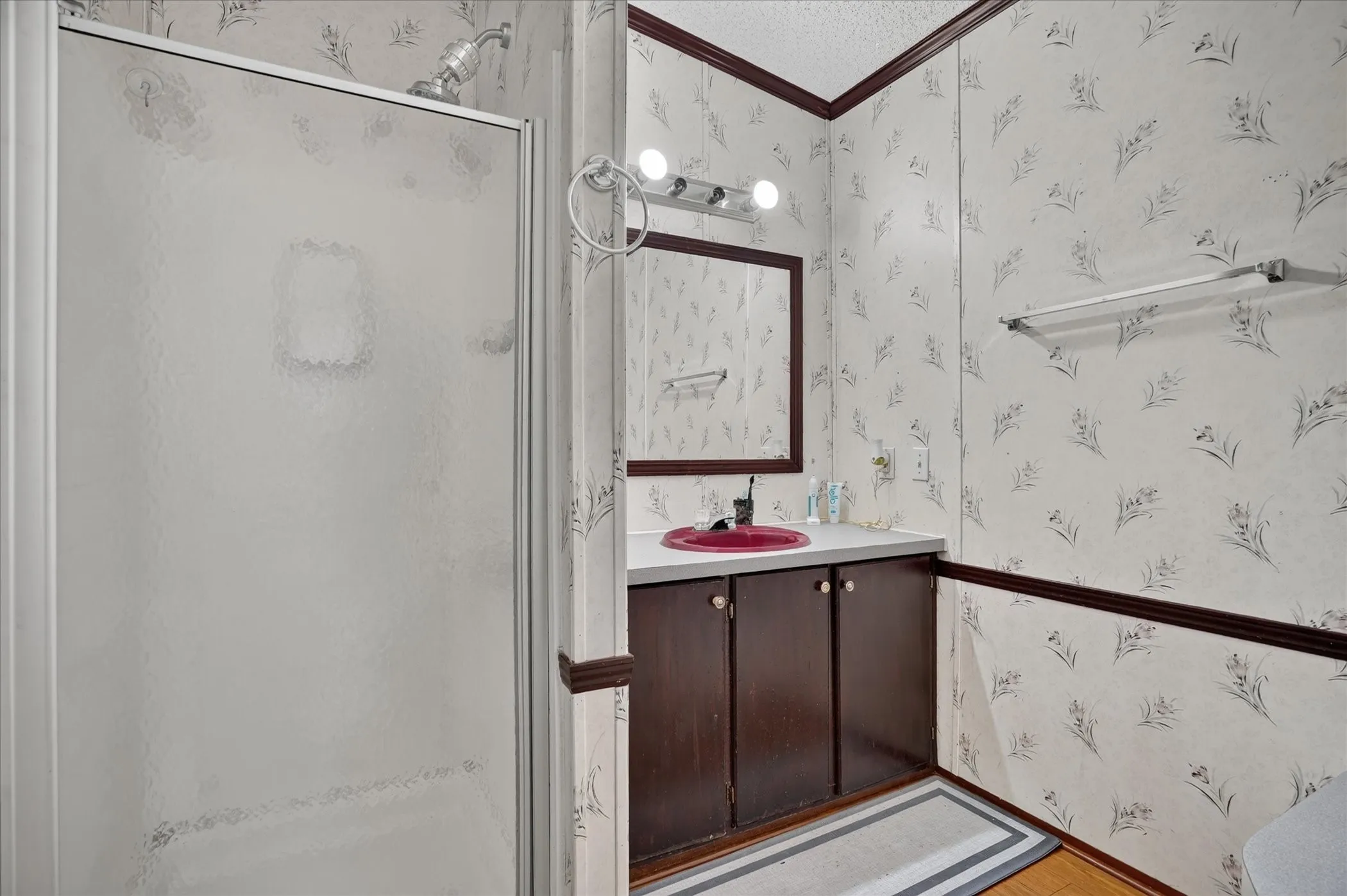 Shower enclosure with frosted glass, single vanity with red vessel sink, wall-mounted mirror, and decorative wall paneling