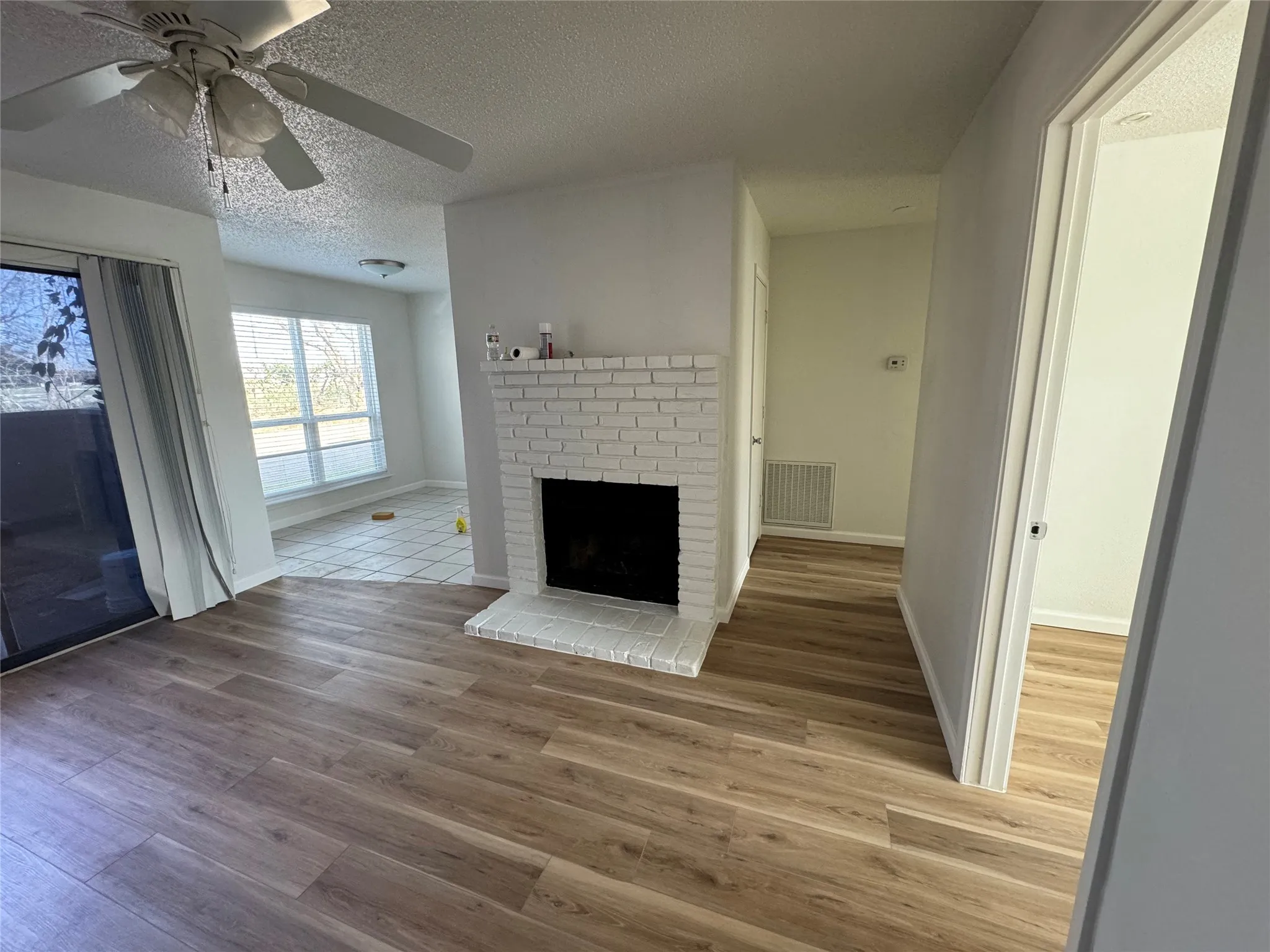 Unfurnished living room featuring a textured ceiling, wood finished floors, a fireplace, and visible vents