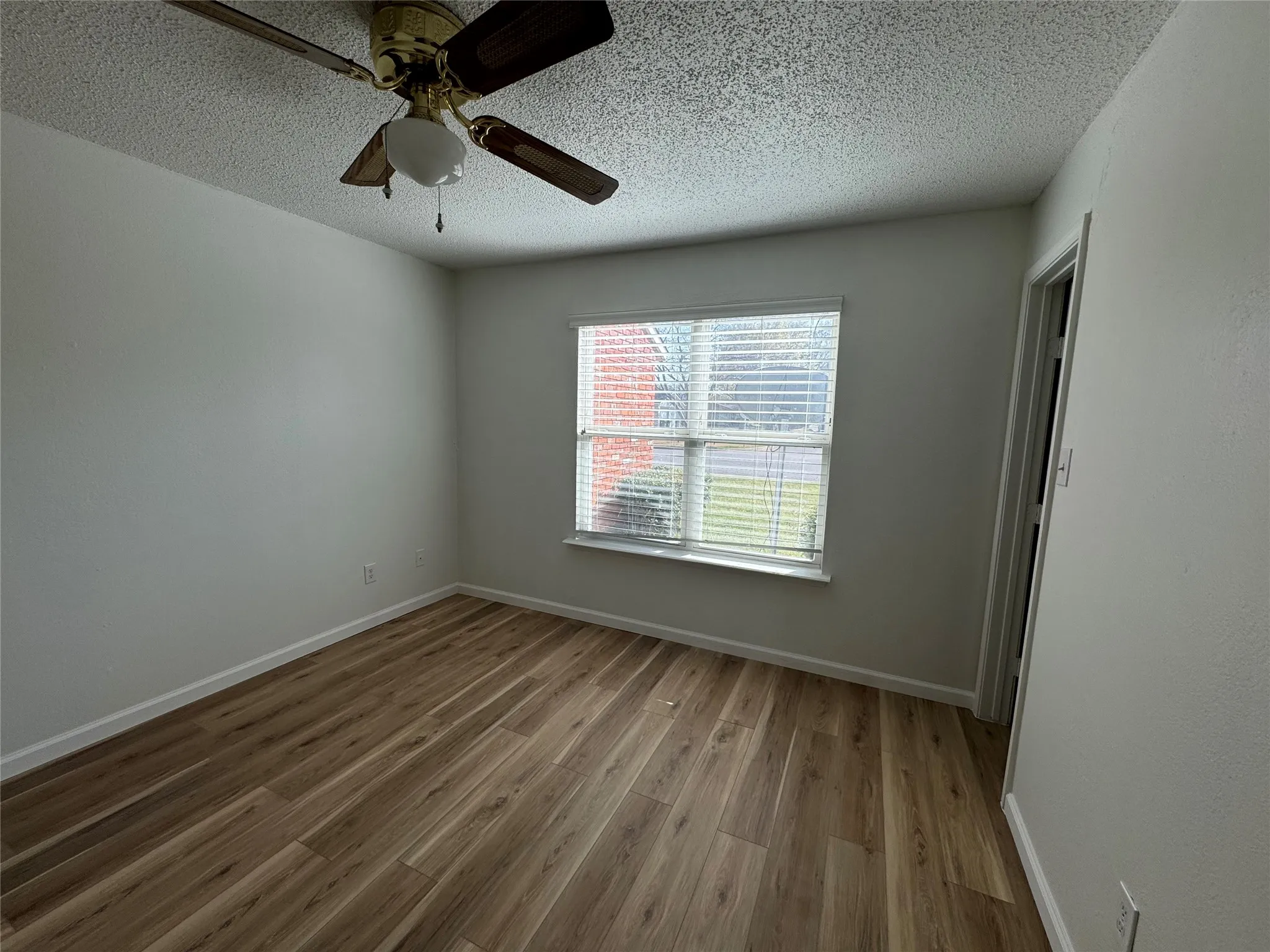 Spare room with baseboards, wood finished floors, and a textured ceiling