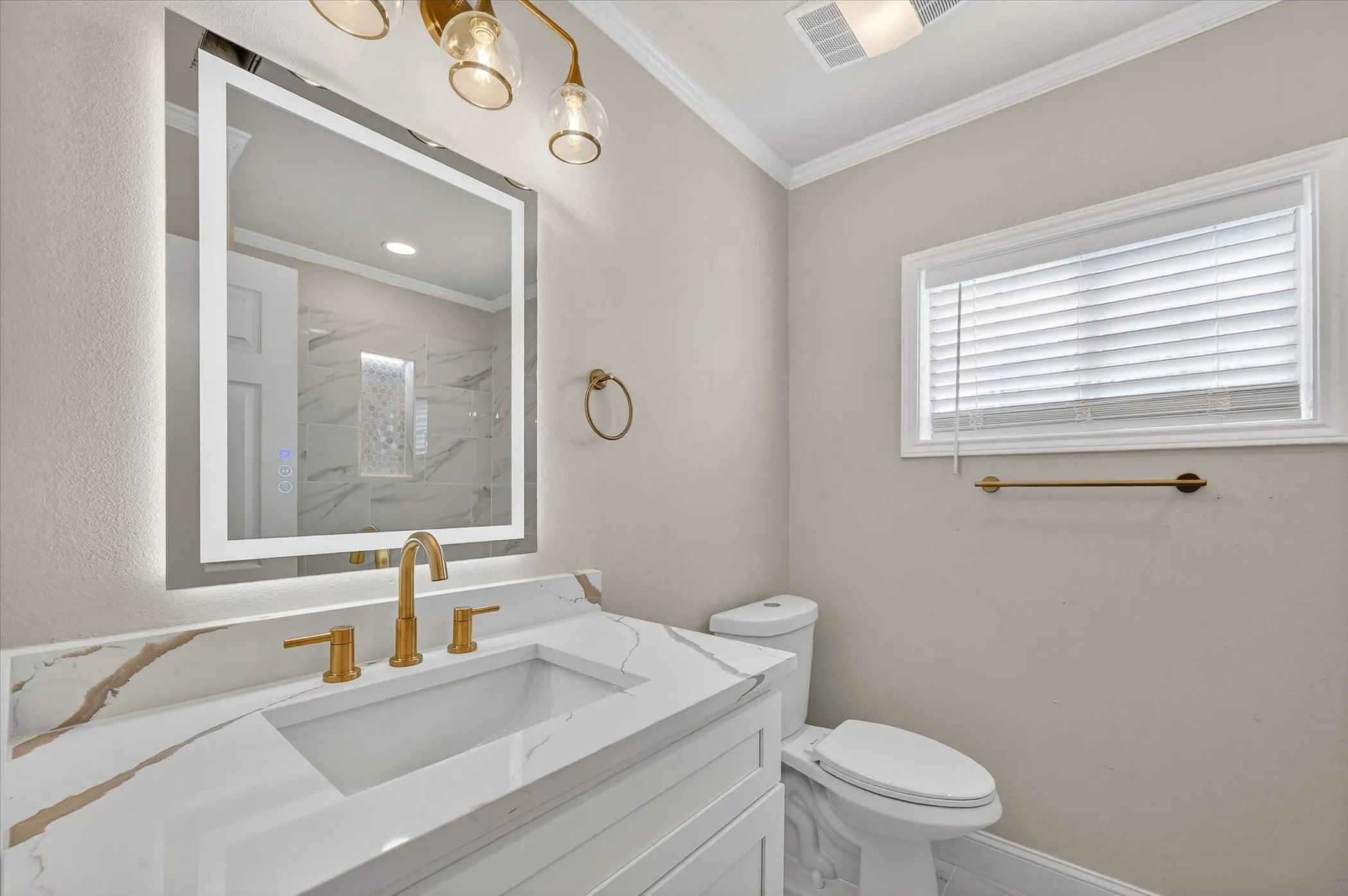 Vanity with integrated rectangular sink, gold-finish faucet, and veined countertop