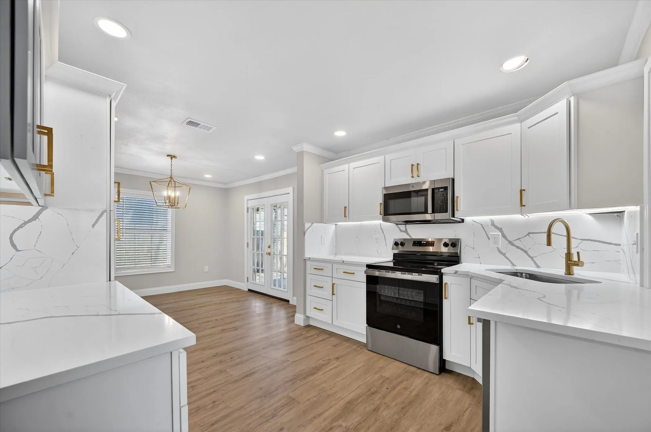 Kitchen featuring white cabinetry, integrated stainless steel appliances, light-toned countertops with a matching backsplash, and wood-finish flooring