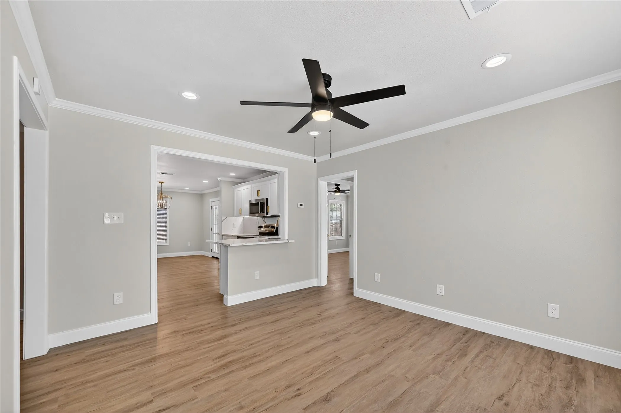 Recessed lighting, crown molding, wood-finish flooring, ceiling fan, and a pass-through counter