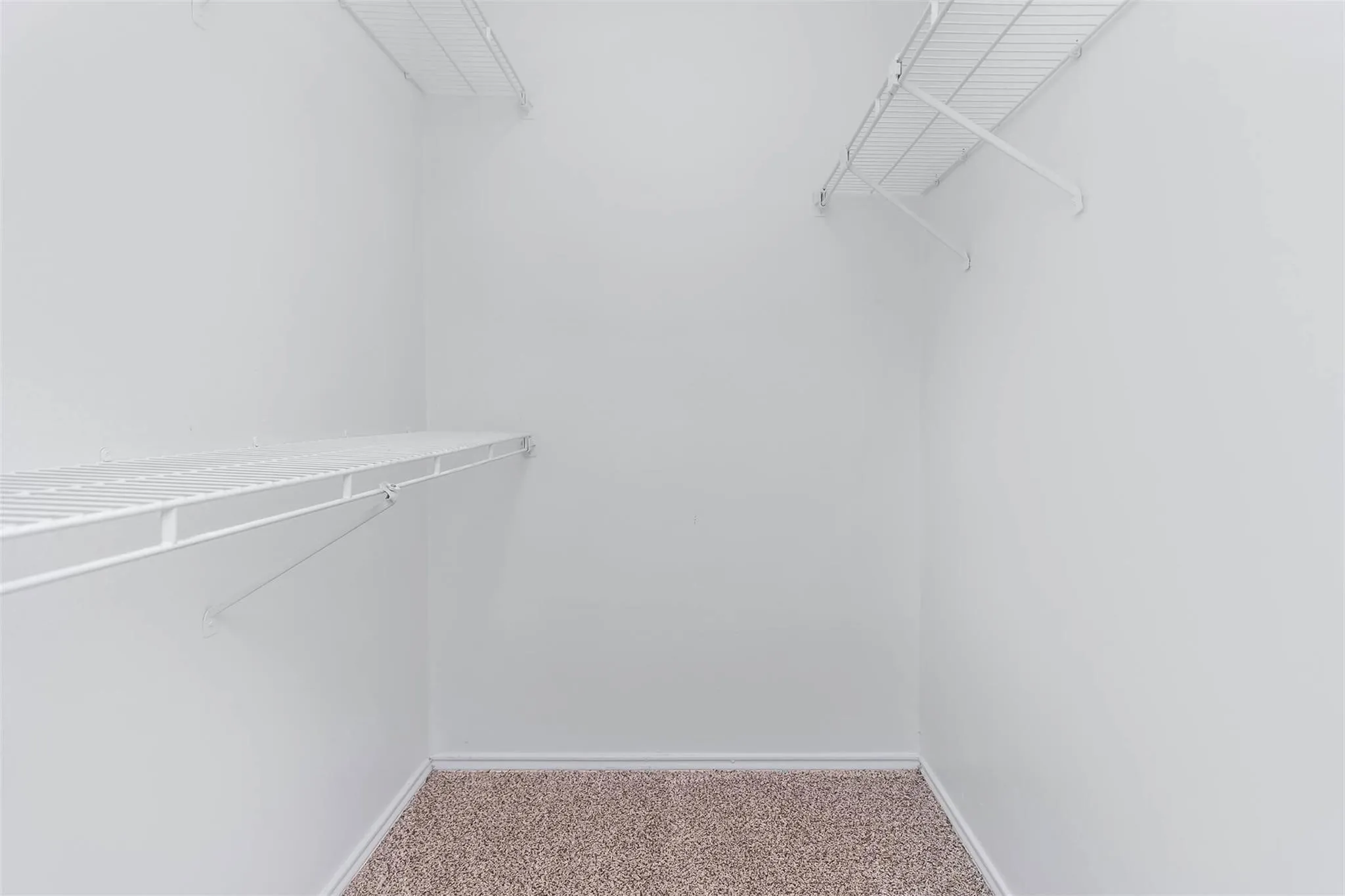 Built-in wire shelving, white wall finish, and neutral-tone carpet flooring