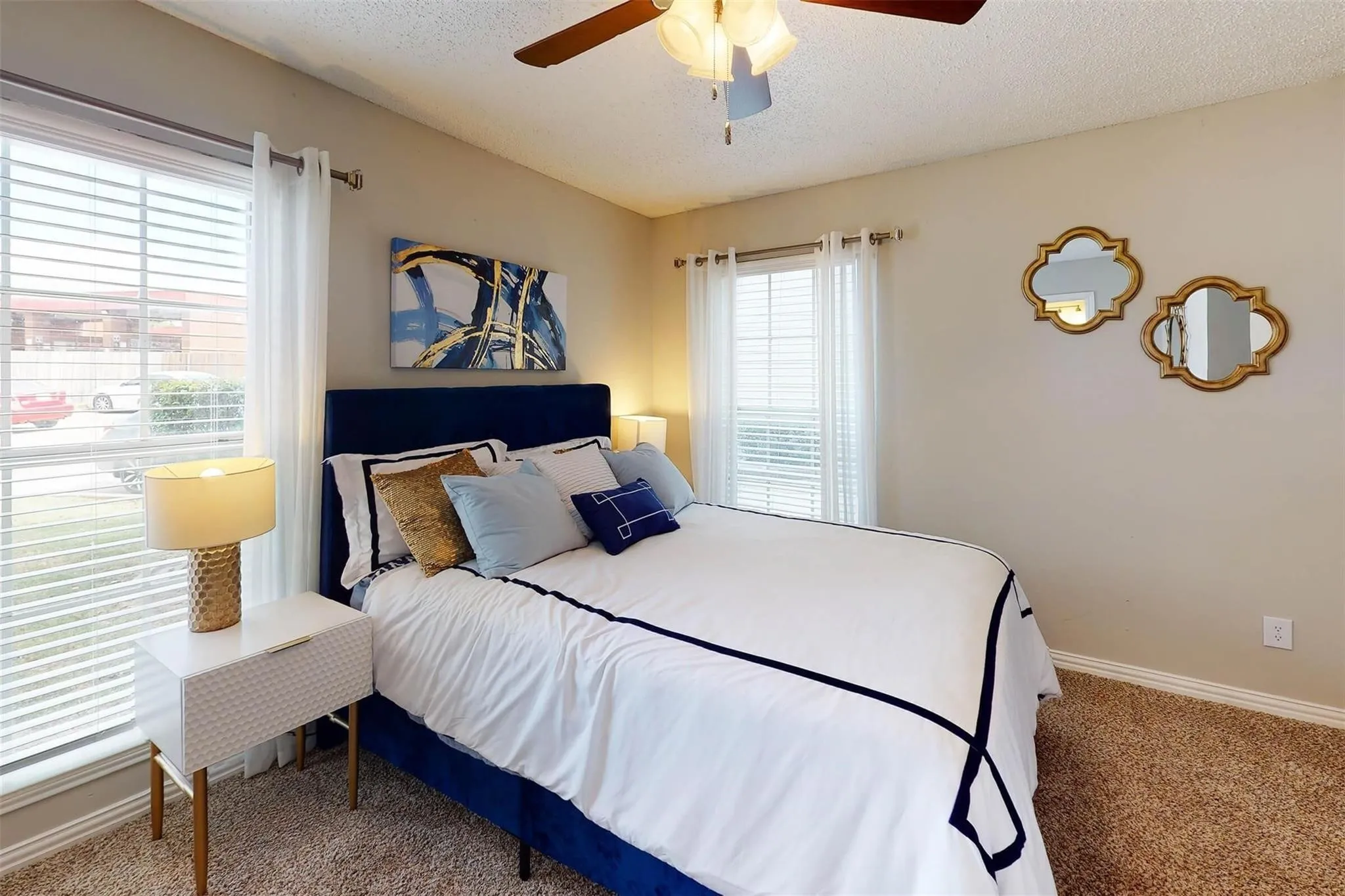 Carpeted flooring with dual windows featuring blinds and sheer curtains