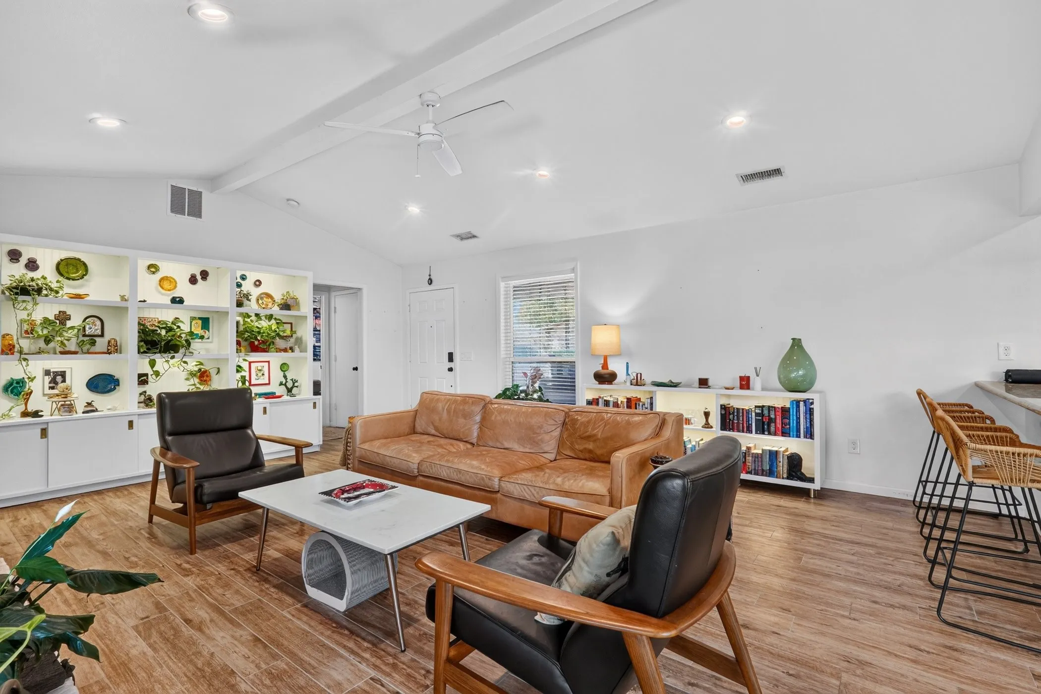 Vaulted ceiling with a ceiling fan, recessed lighting, wood-finish flooring, built-in shelving with integrated lighting, and a breakfast bar