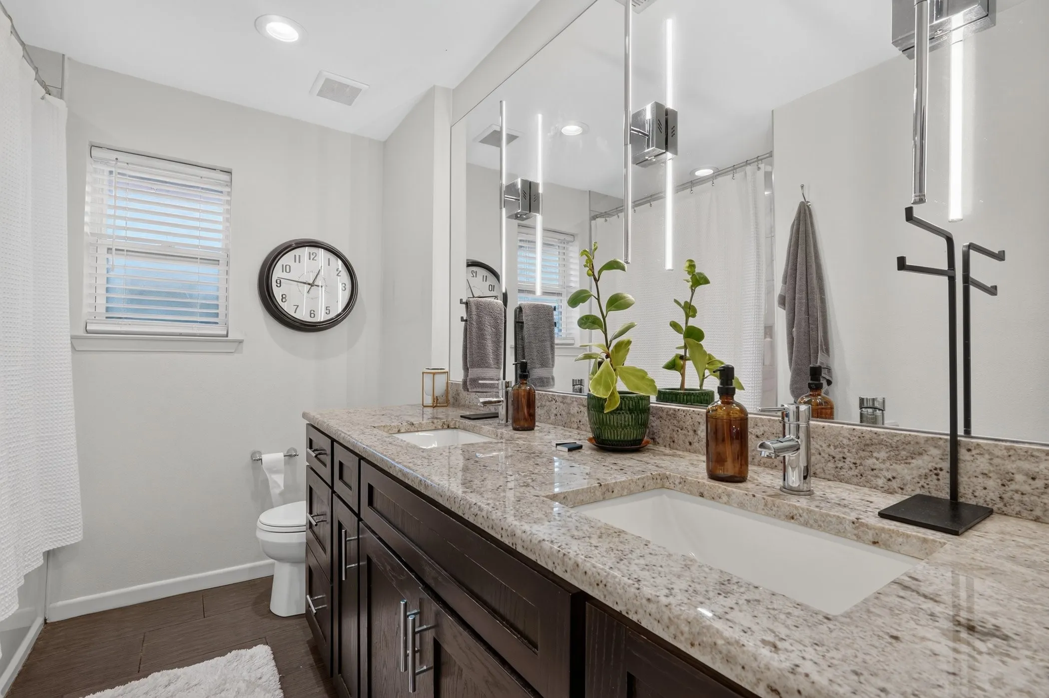 Dual vanity with light-toned countertop, integrated sinks, and dark wood-finish cabinetry