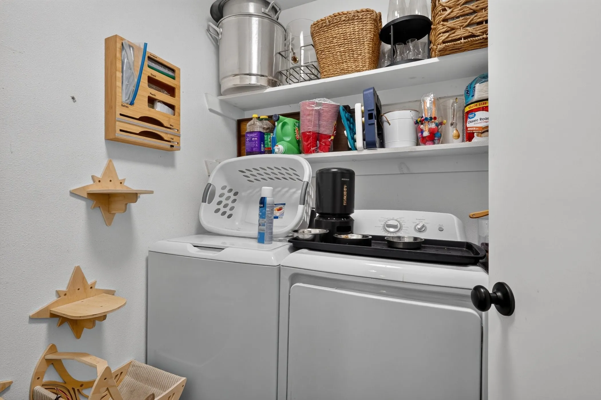Laundry area featuring a stackable washer and dryer, white shelving, and a wall-mounted wooden organizer