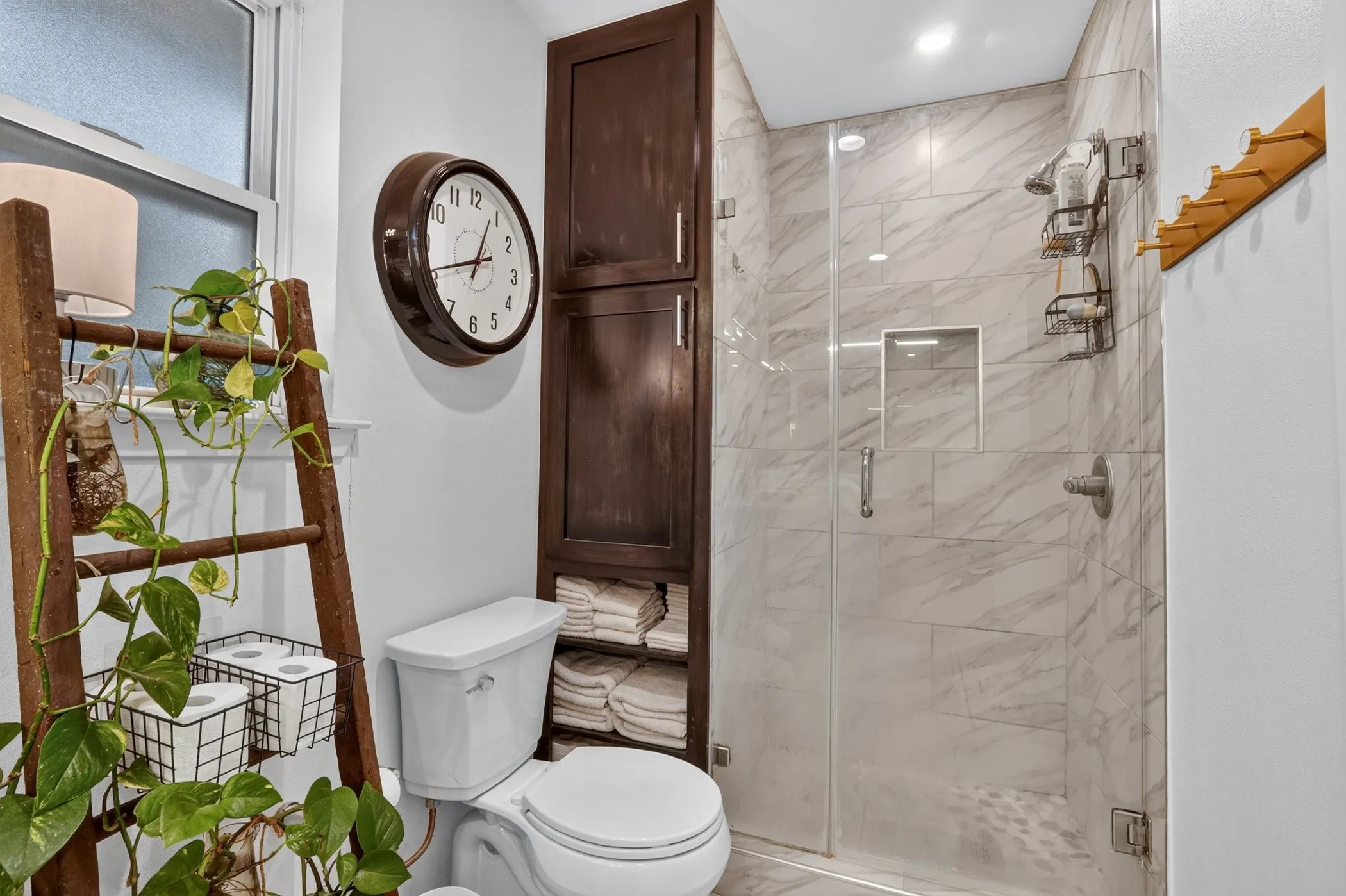 Walk-in shower with clear glass enclosure and marble-look tile