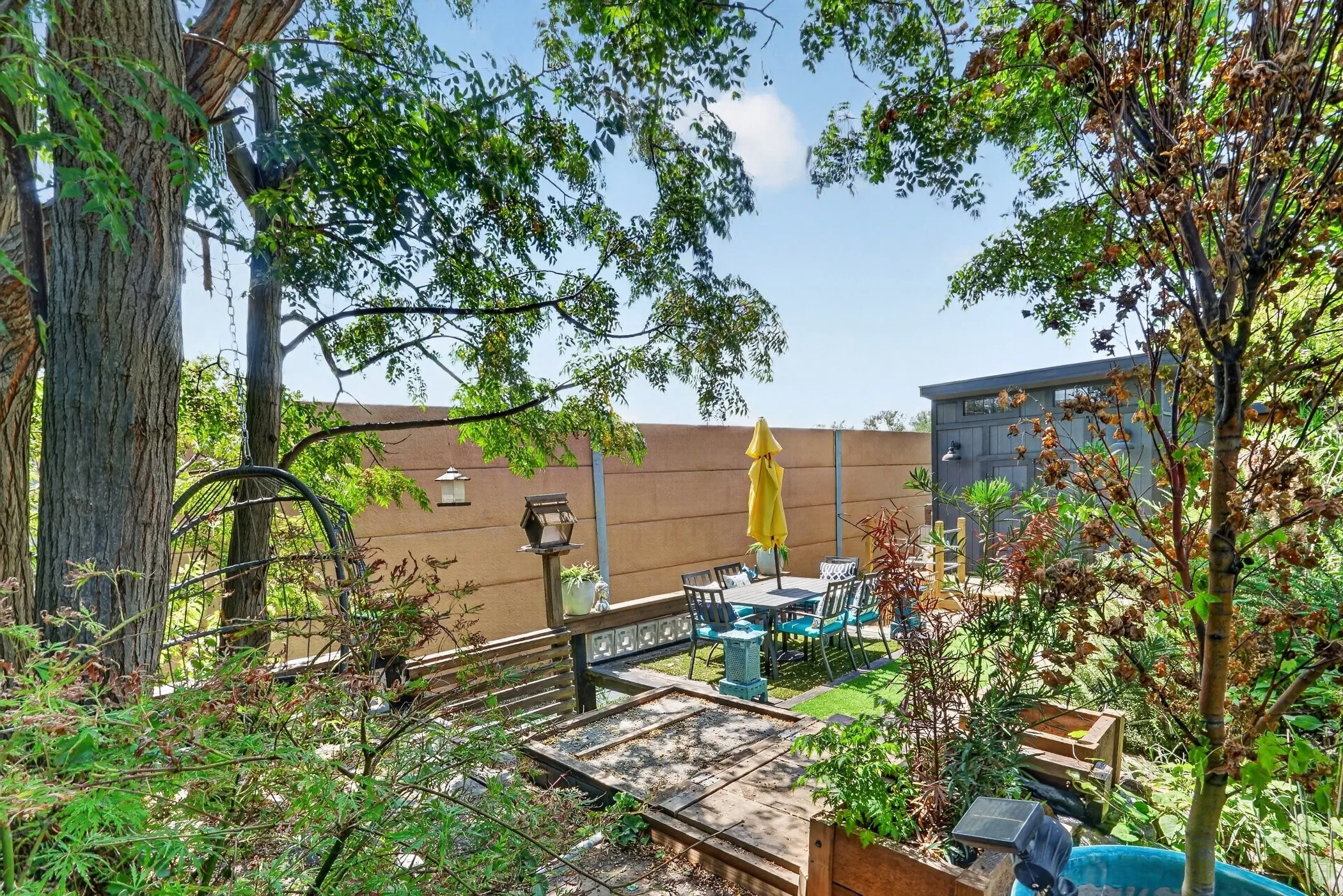 Private outdoor space with mature trees, a privacy fence, and a patio area