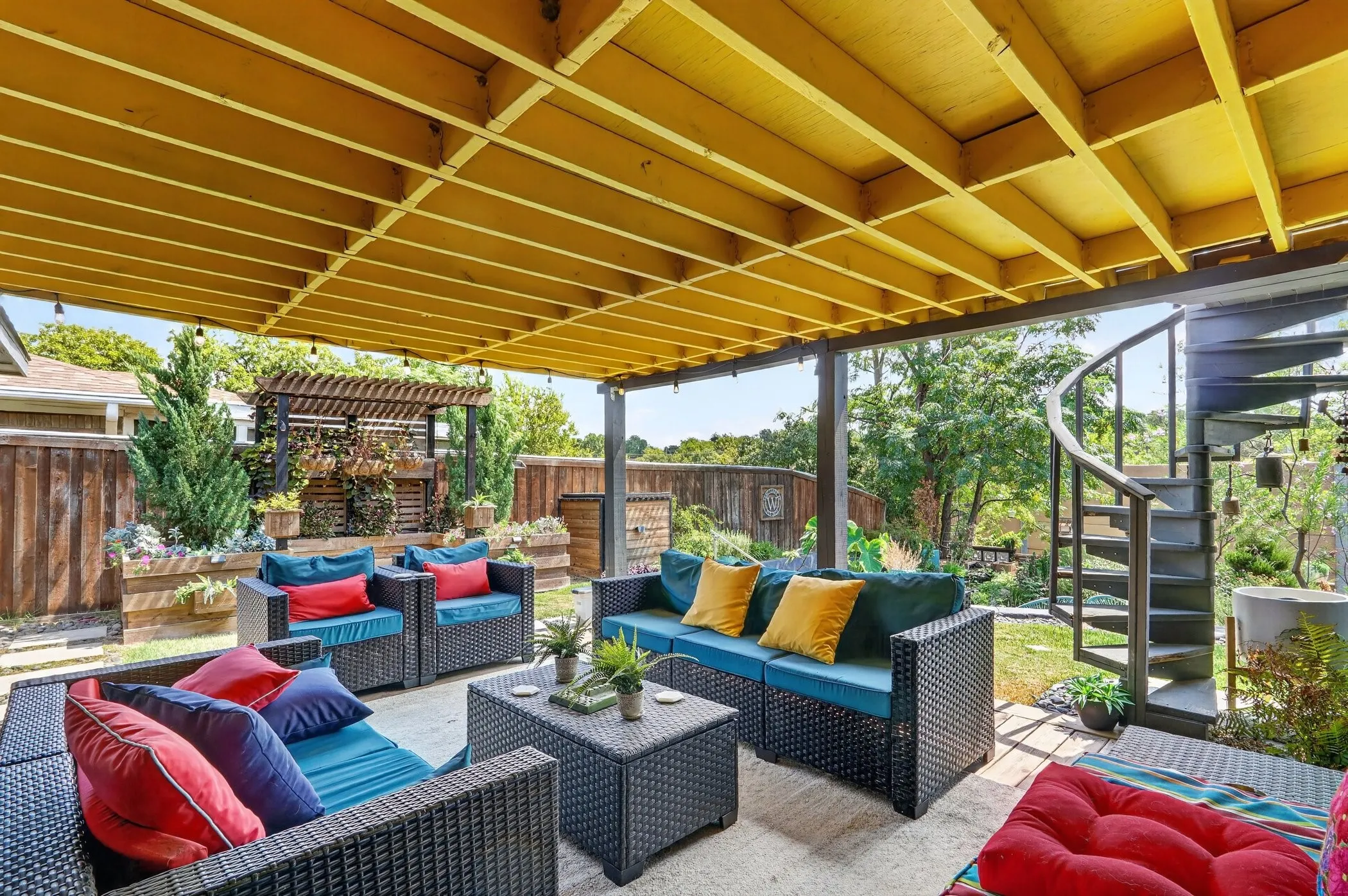 Expansive covered patio featuring a concrete surface, exposed yellow ceiling beams, and a black spiral staircase