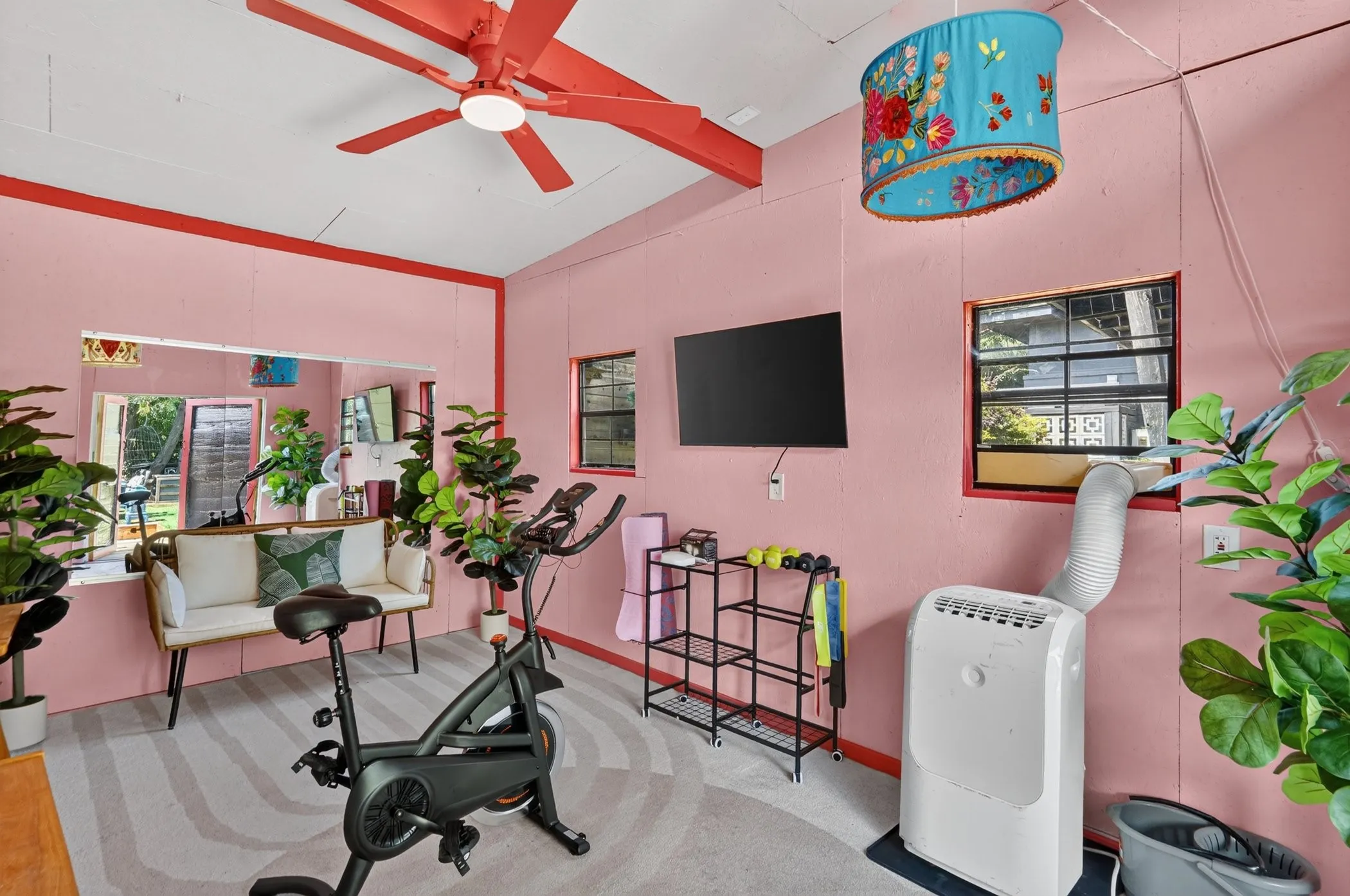 Vaulted ceiling with exposed beams, ceiling fan, and reflective wall panel