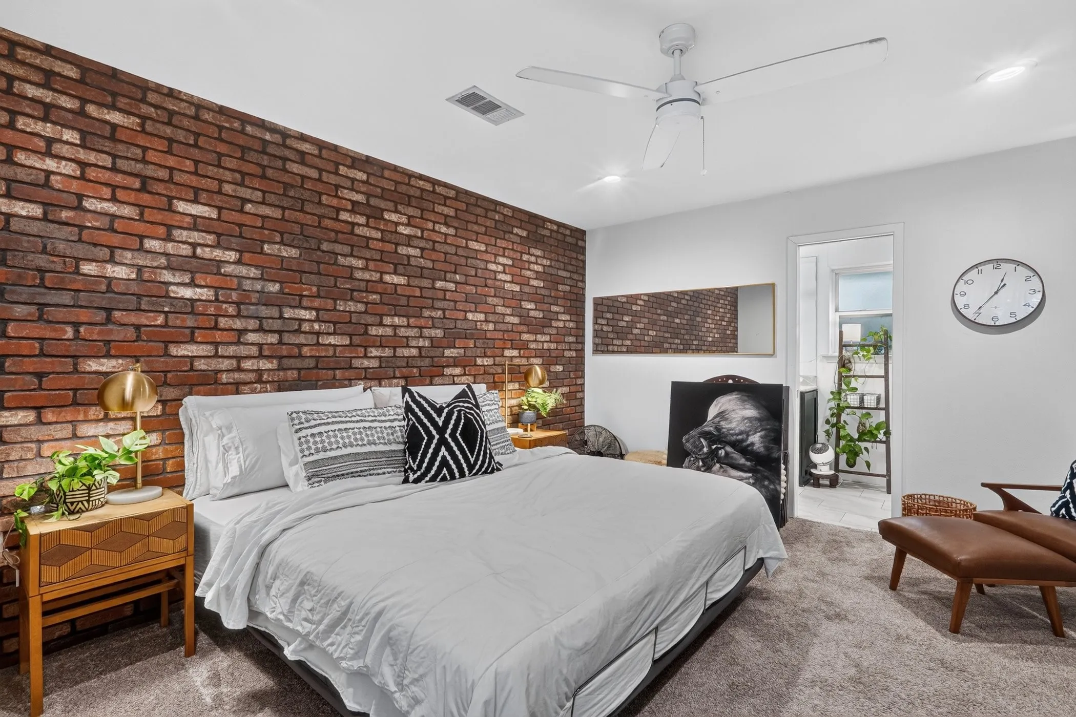 Exposed brick accent wall, ceiling fan with integrated lighting, recessed lighting, and soft gray carpeting