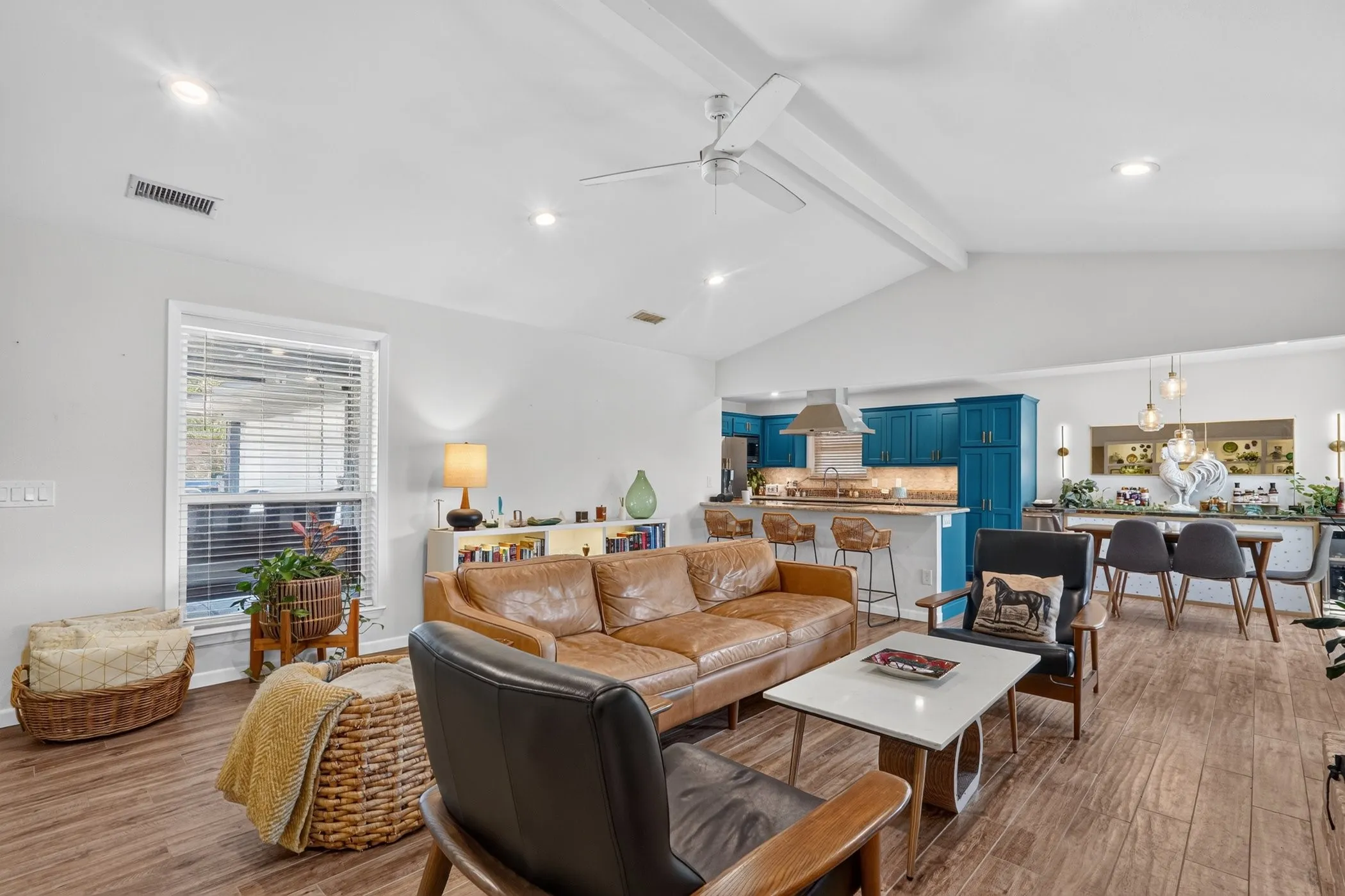 Vaulted ceiling, recessed lighting, wood-finish flooring, kitchen island with seating, and a dining area with pendant lighting
