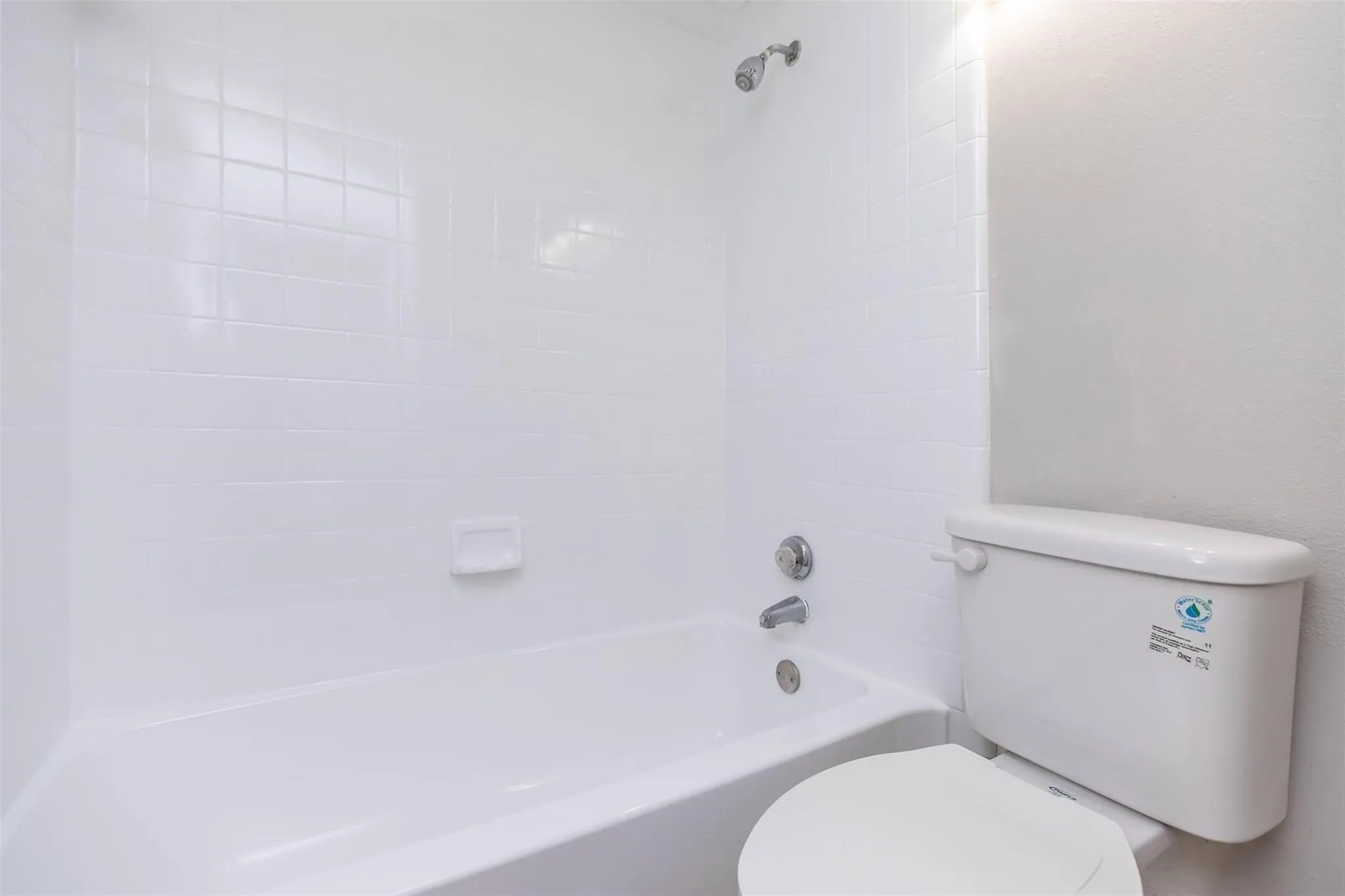 White tiled bath and shower combination with chrome fixtures
