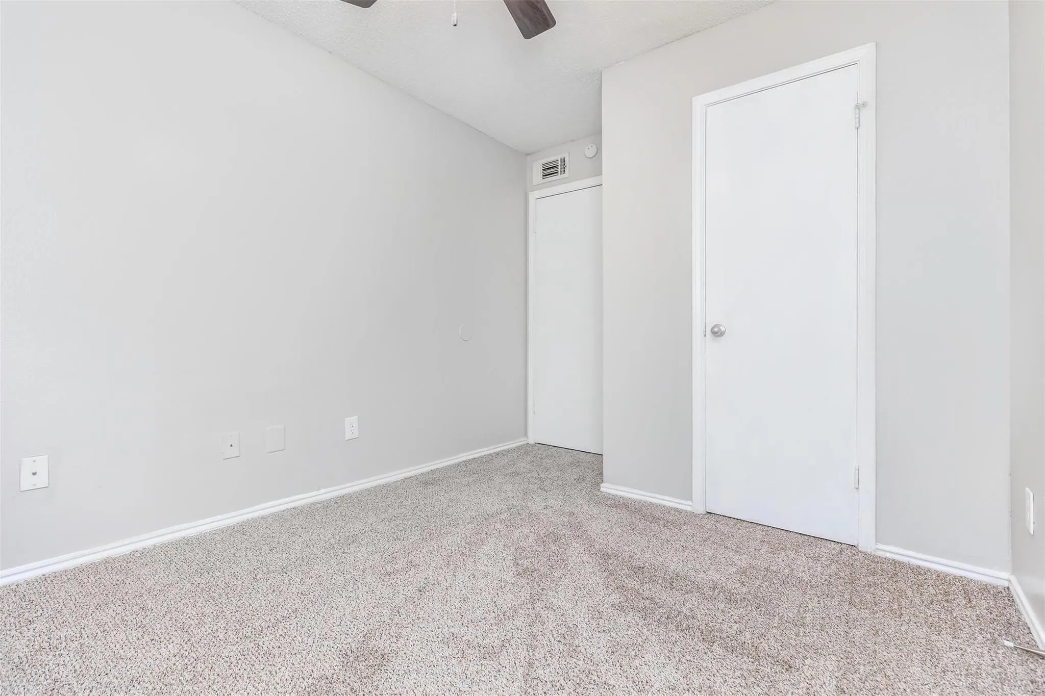 Plush carpet flooring, light neutral wall color, and a ceiling fan
