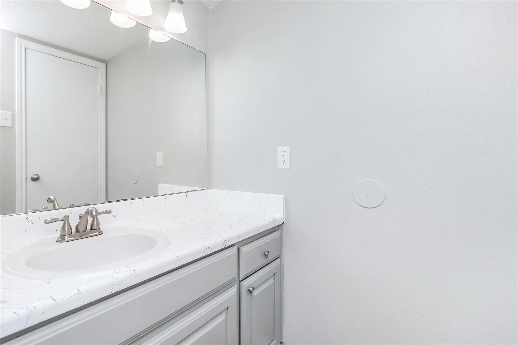 Vanity with an integrated rectangular sink, brushed nickel faucet, and a large wall-mounted mirror